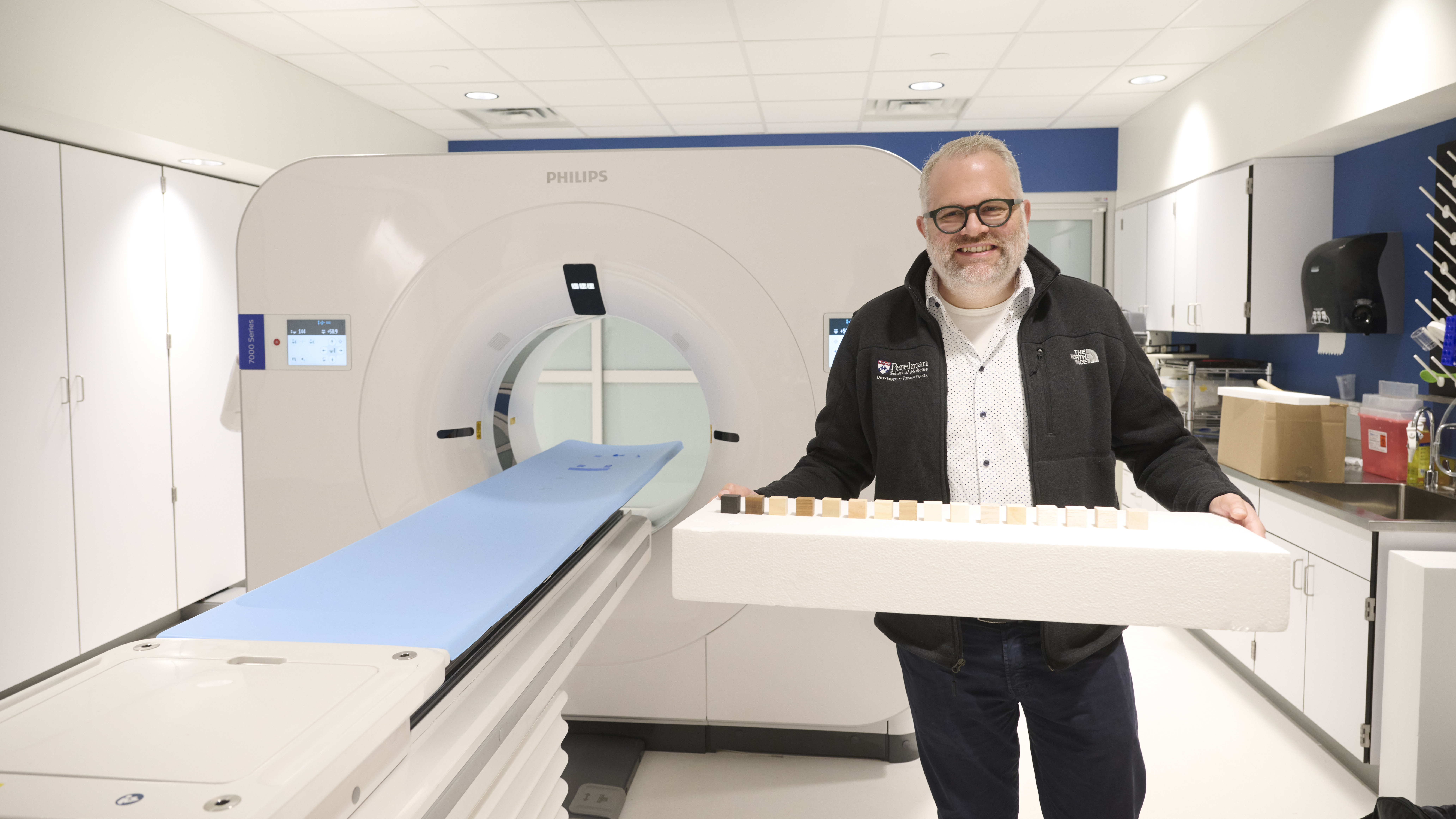 Peter Noël holding a bass holder while standing next to the CT scanner