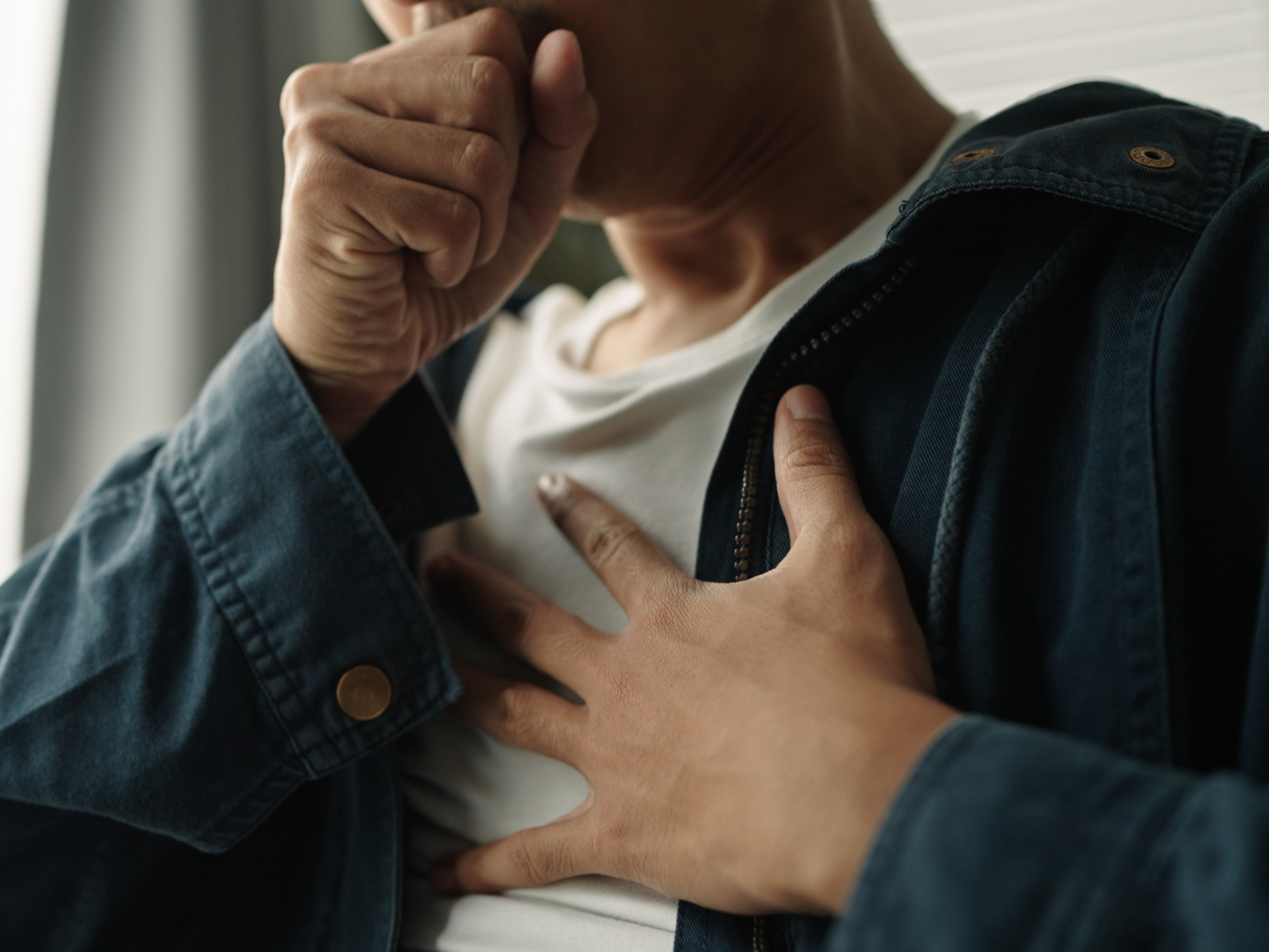Young man coughing, suffering from chest pain from chronic disease