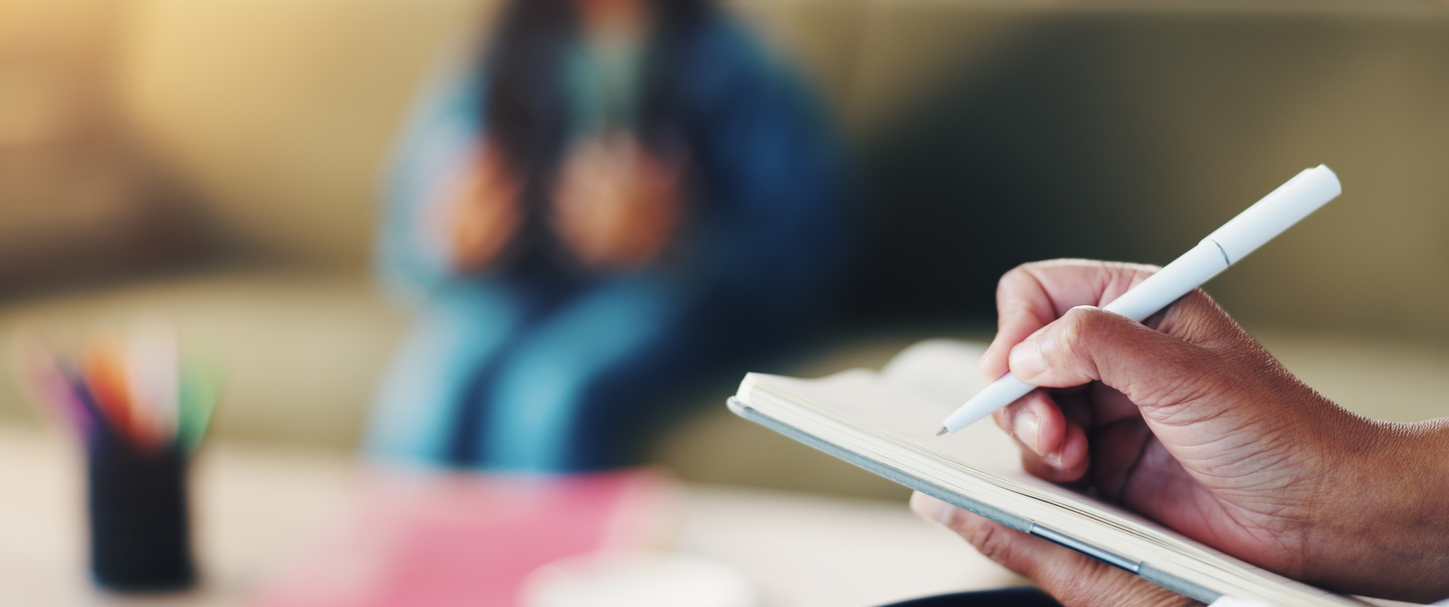 A therapist writes notes while their patient talks