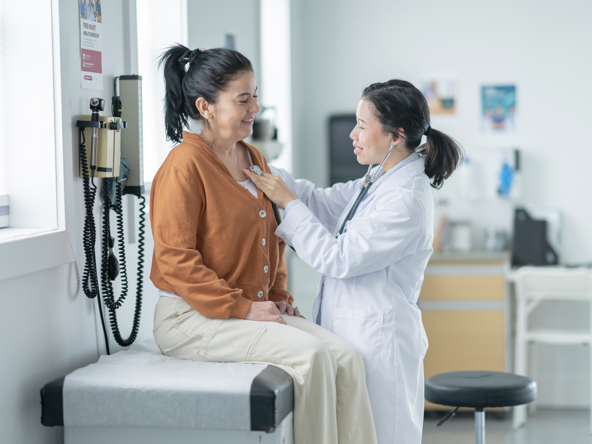 Doctor using stethoscope on female patient.