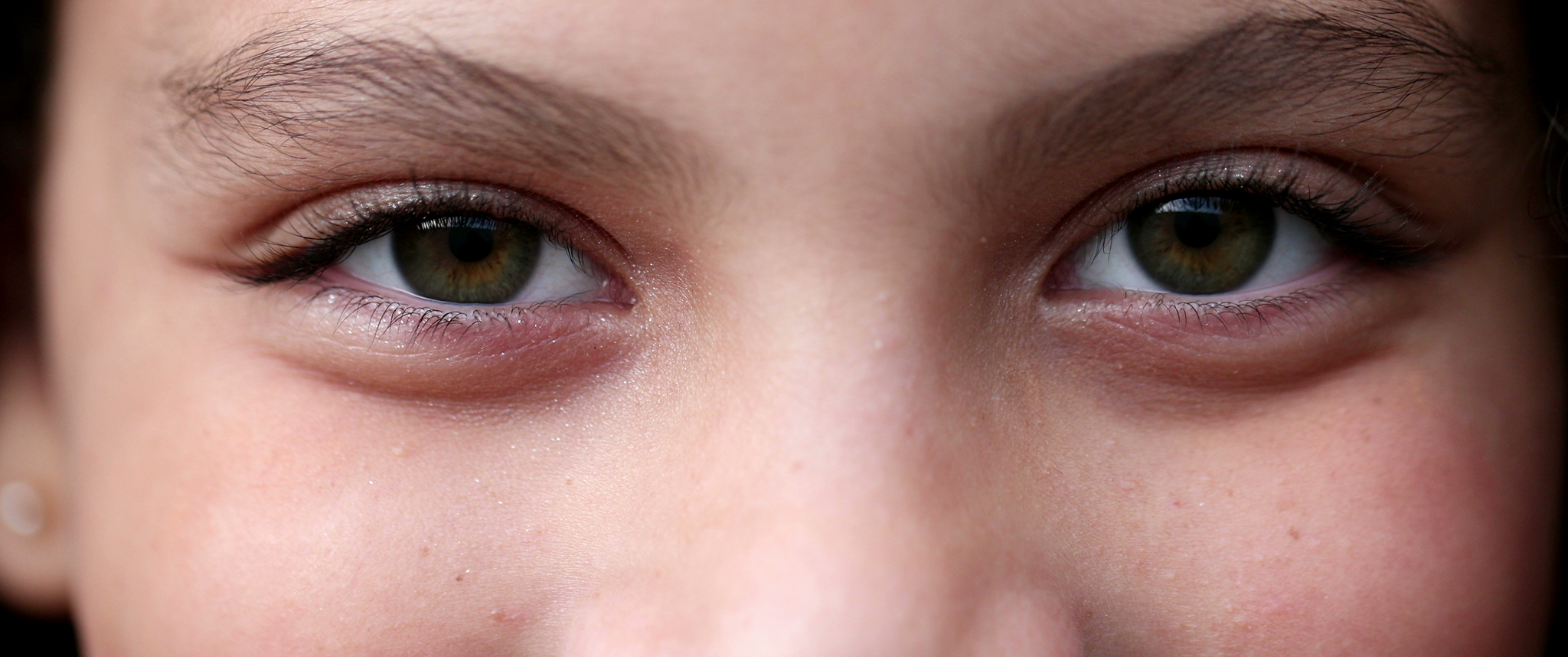 Child closing and opening eyes and smiling, macro green eyes close-up