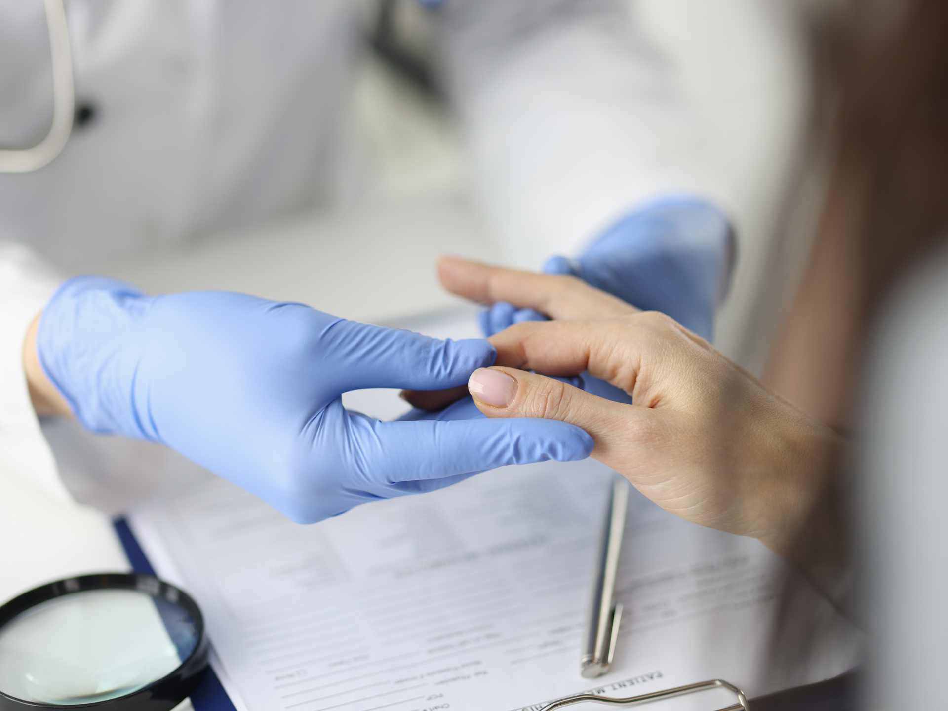  Doctor in gloves examines finger in a medical office.