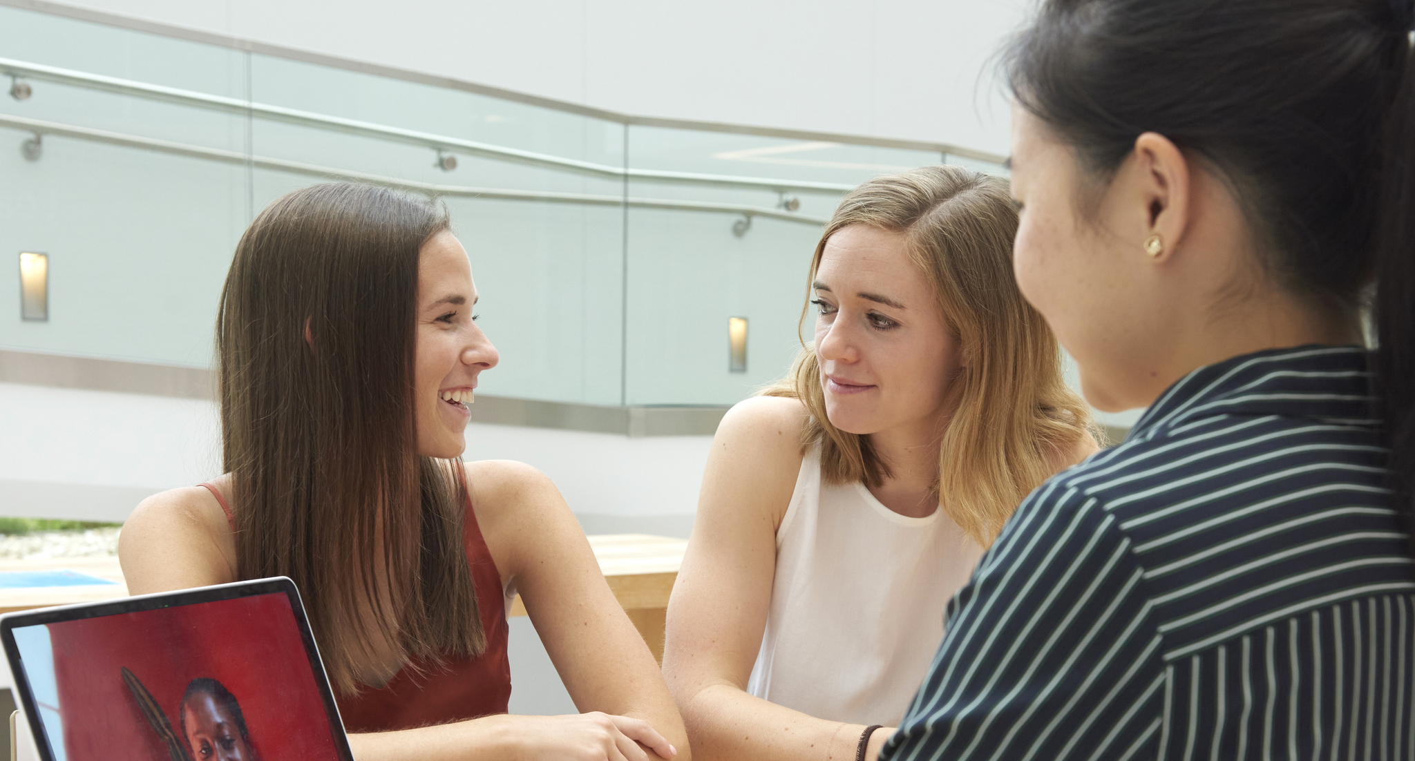 Angela Malinovitch, Danielle Brown, and Emily Xu sit at a desk with a laptop having a video chat with entrepreneur Whitney Robinson