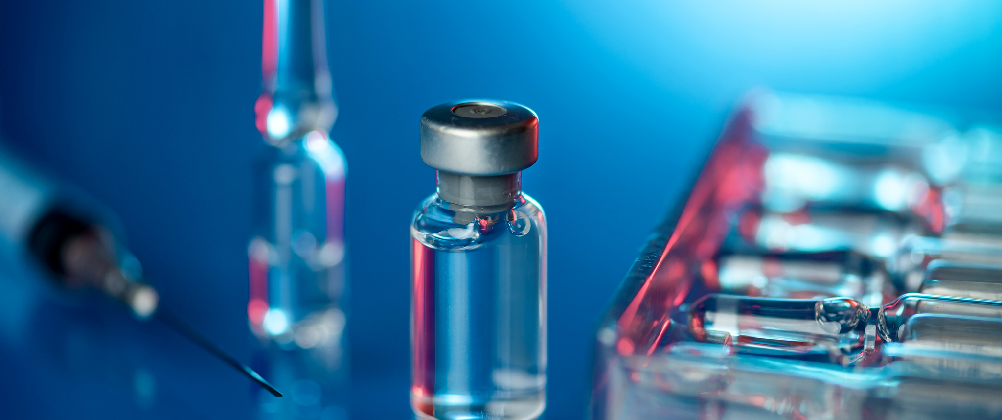 Close up shot of vaccines - glass bottles, ampules and syringe with needle
