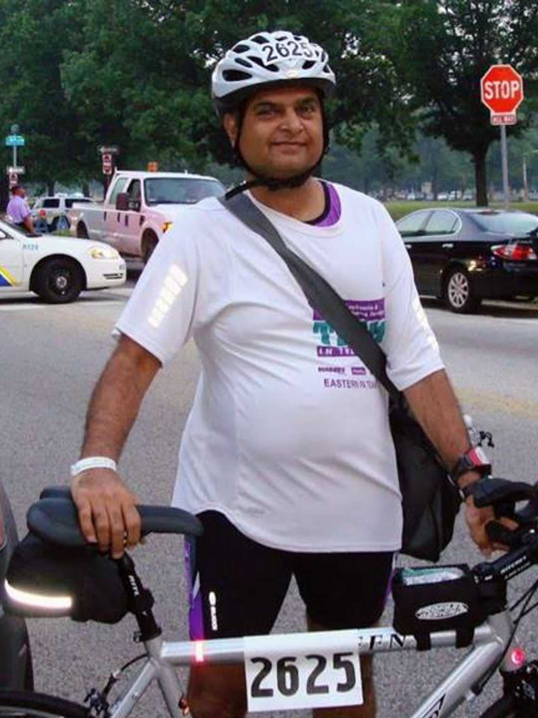 Sanjay Shah wears a helmet and stands next to his bike