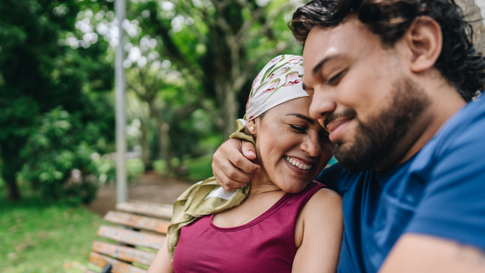 A mature woman who is battling cancer embracing with her husband at park