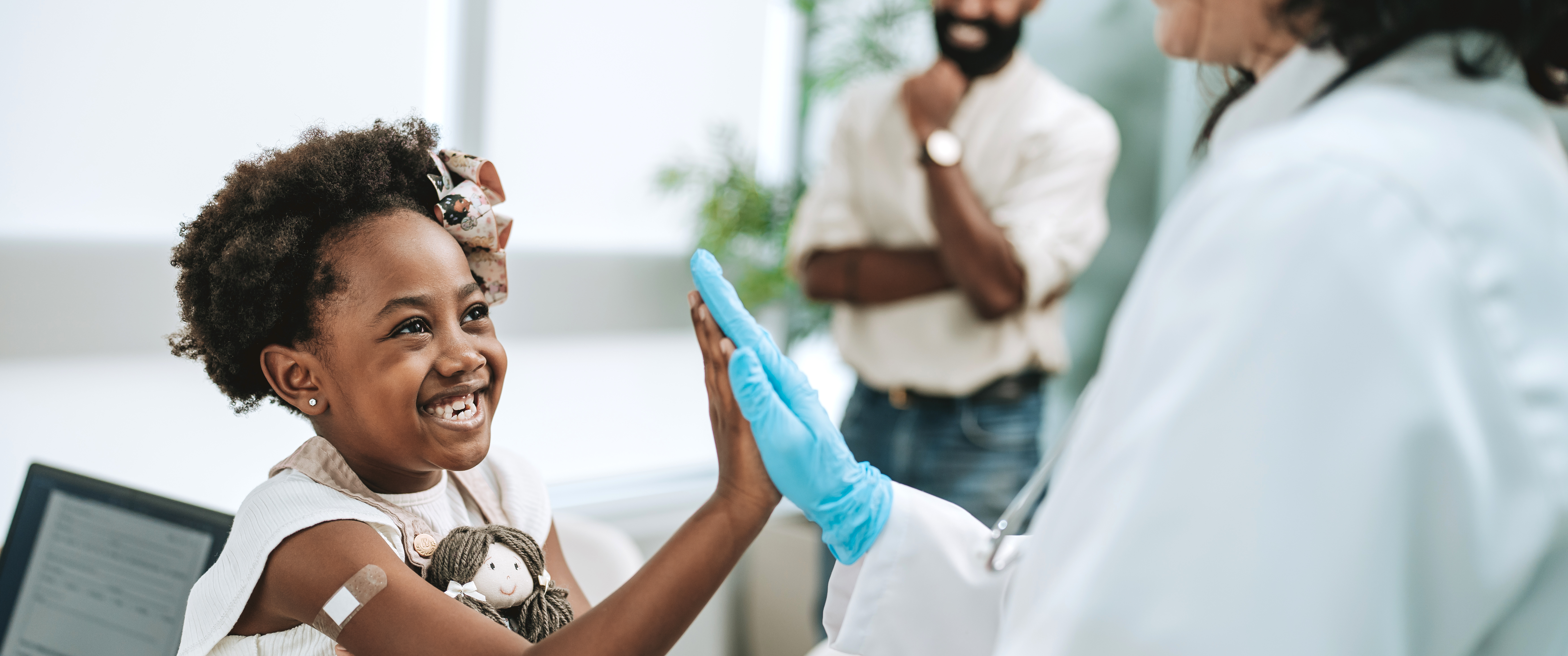A child smiling and high-fiving doctor after a vaccine shot