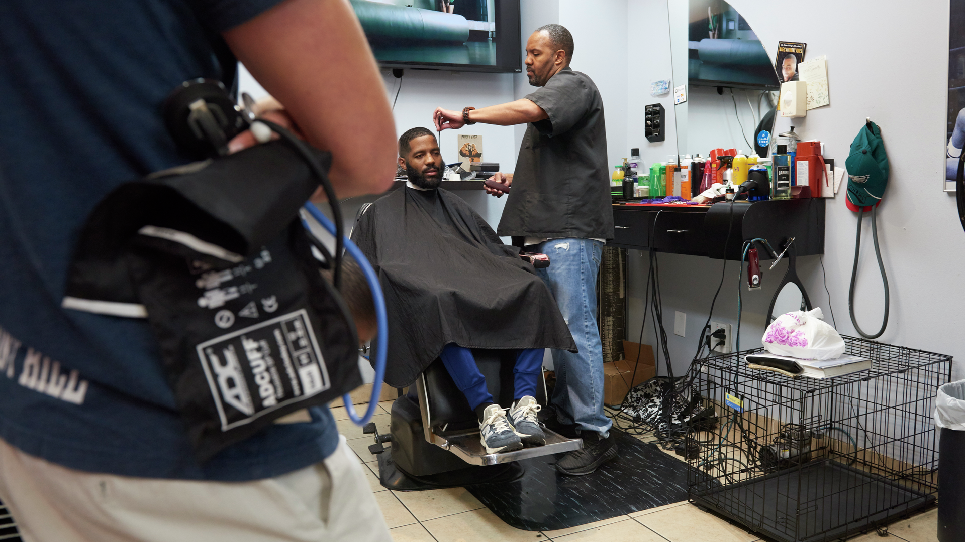 Darryl Thomas cuts a man's hair in a barbershop chair