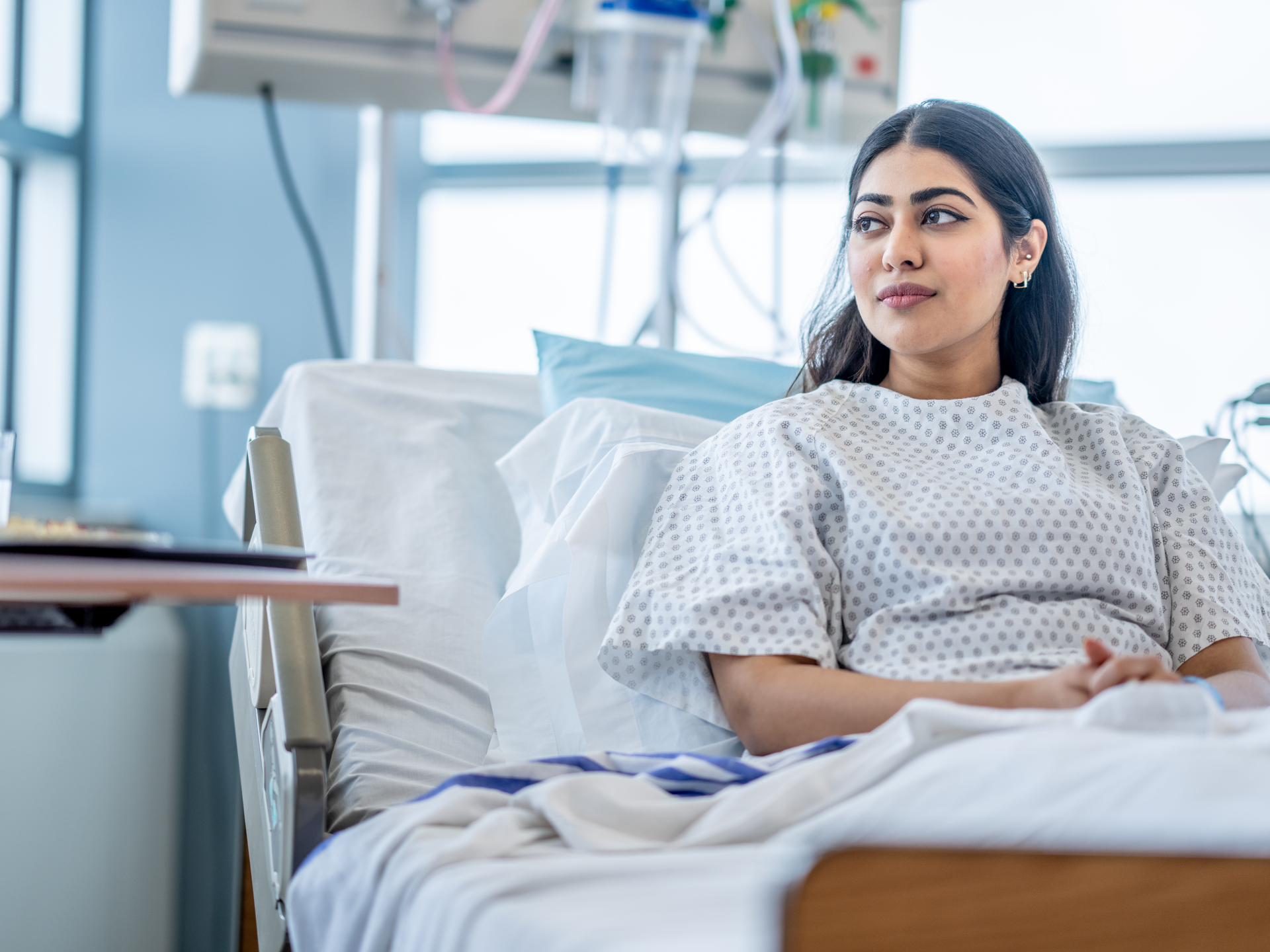 A young woman sit up in her hospital bed after surgery
