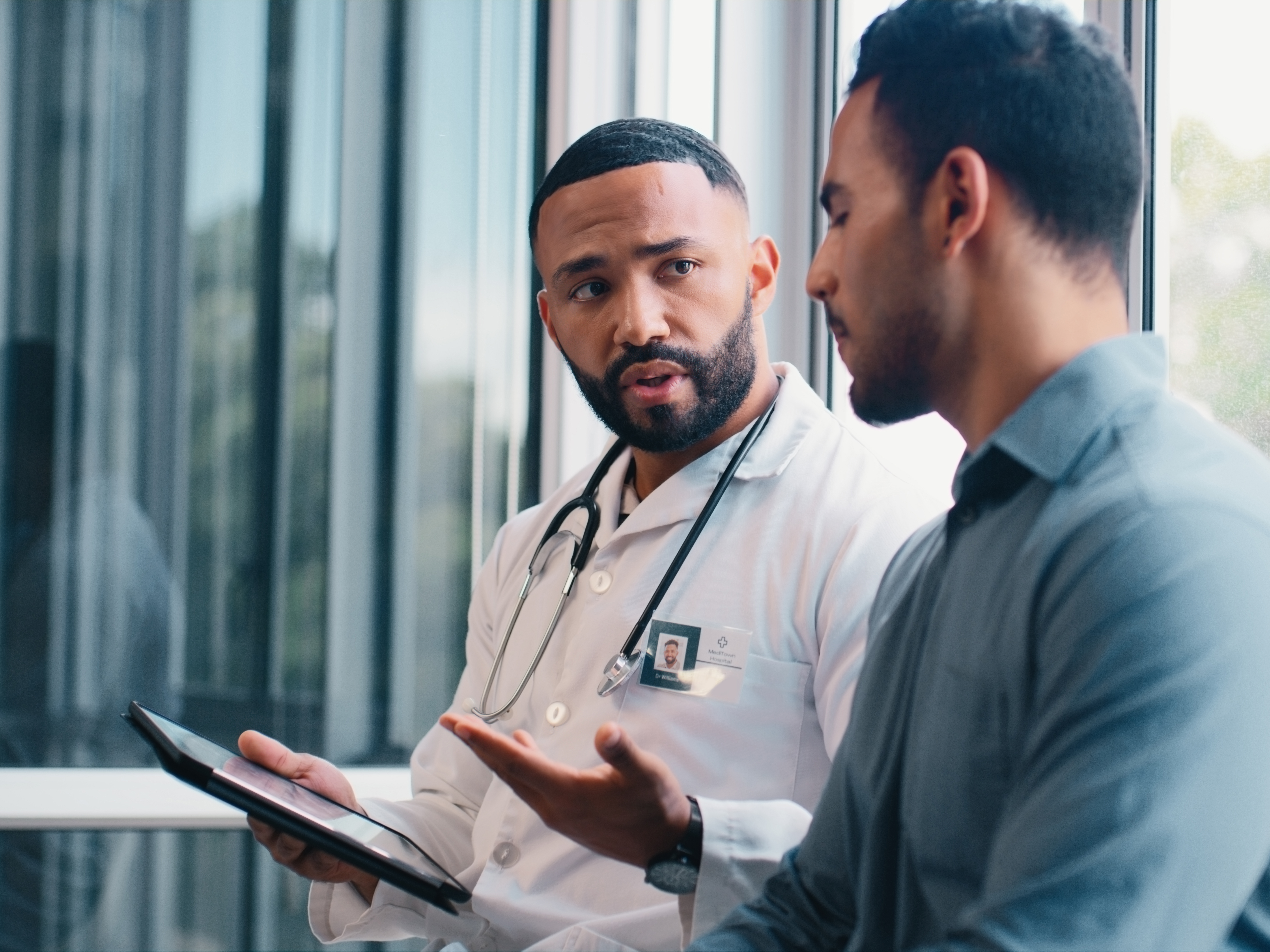 Doctor with tablet consulting with male patient.