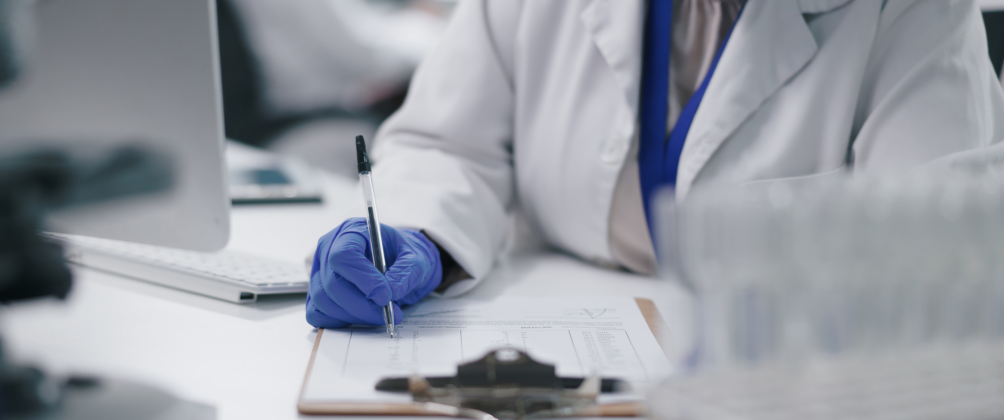 A scientist writes on a clipboard at a desk