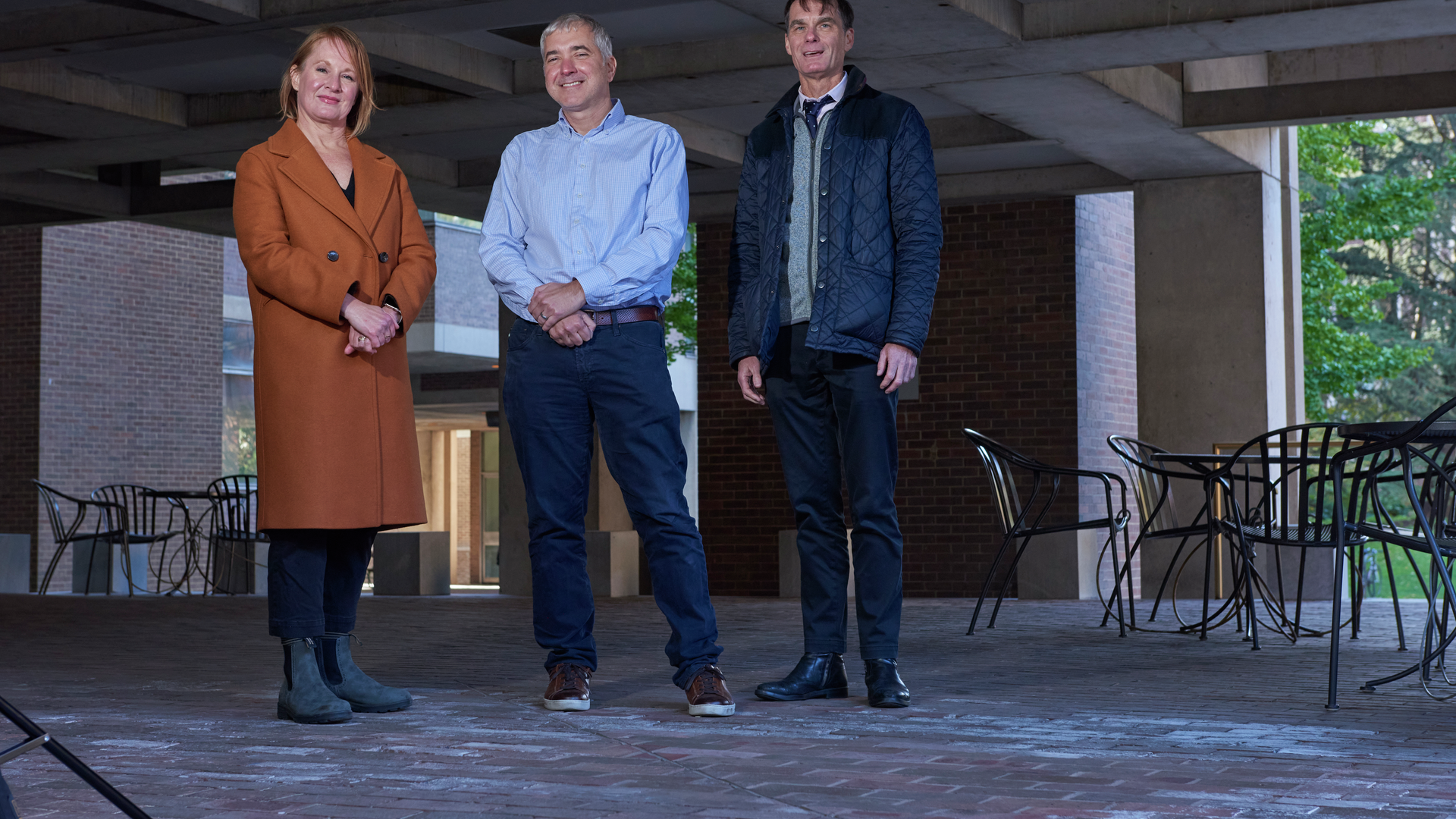 Felicia Greenfield, David Wolk, and Jason Karlawish stand on a covered patio wearing winter coats