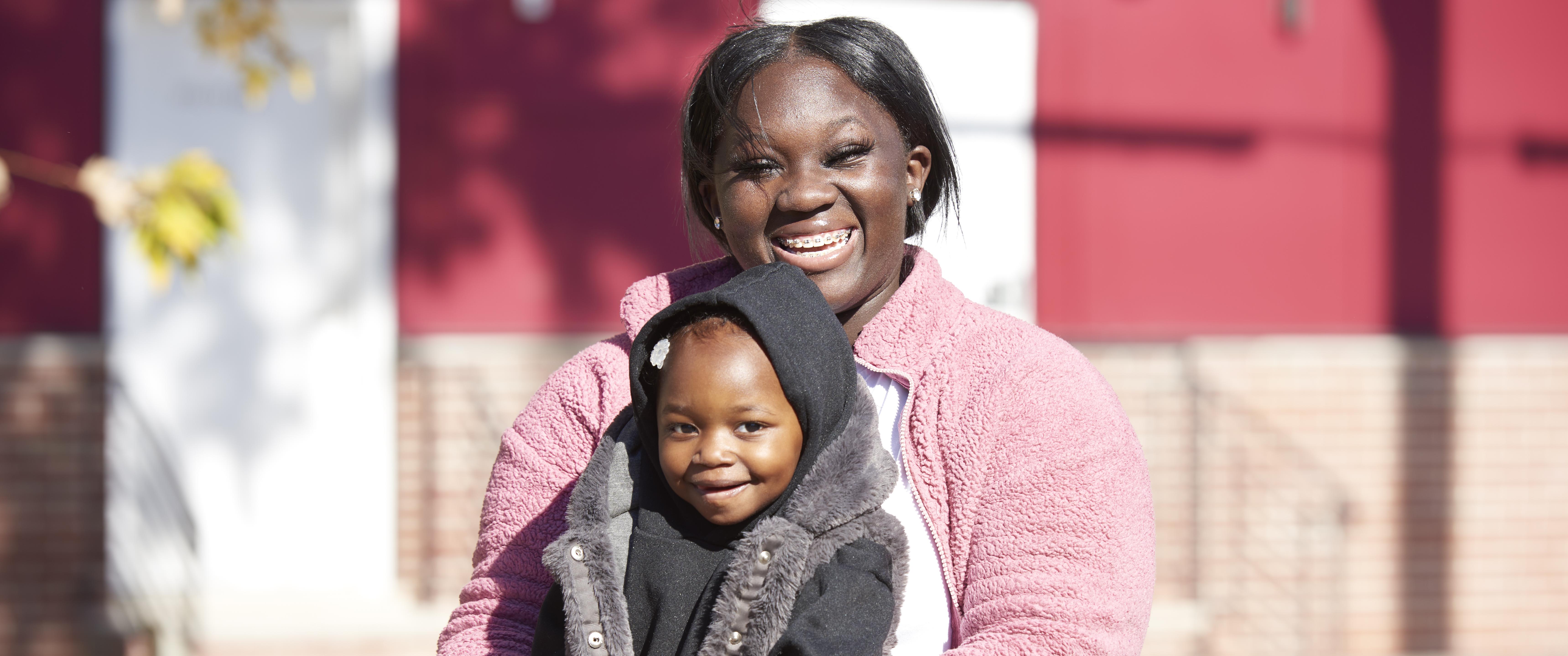 Talicia Williams holds her 2-year-old daughter Zahiri outdoors in a park