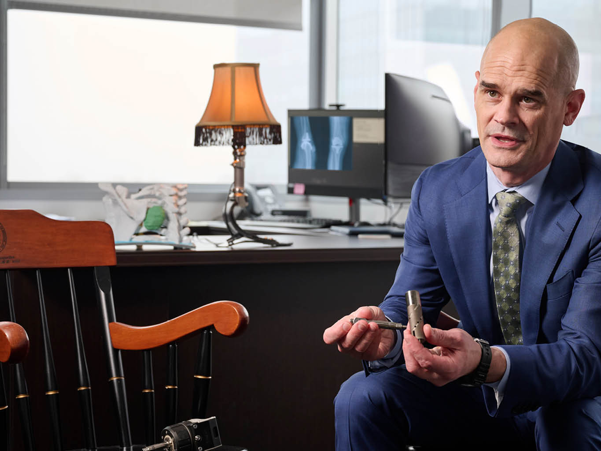 Benjamin “Kyle” Potter, MD, wearing a suit, holding a piece of orthopaedics technology 