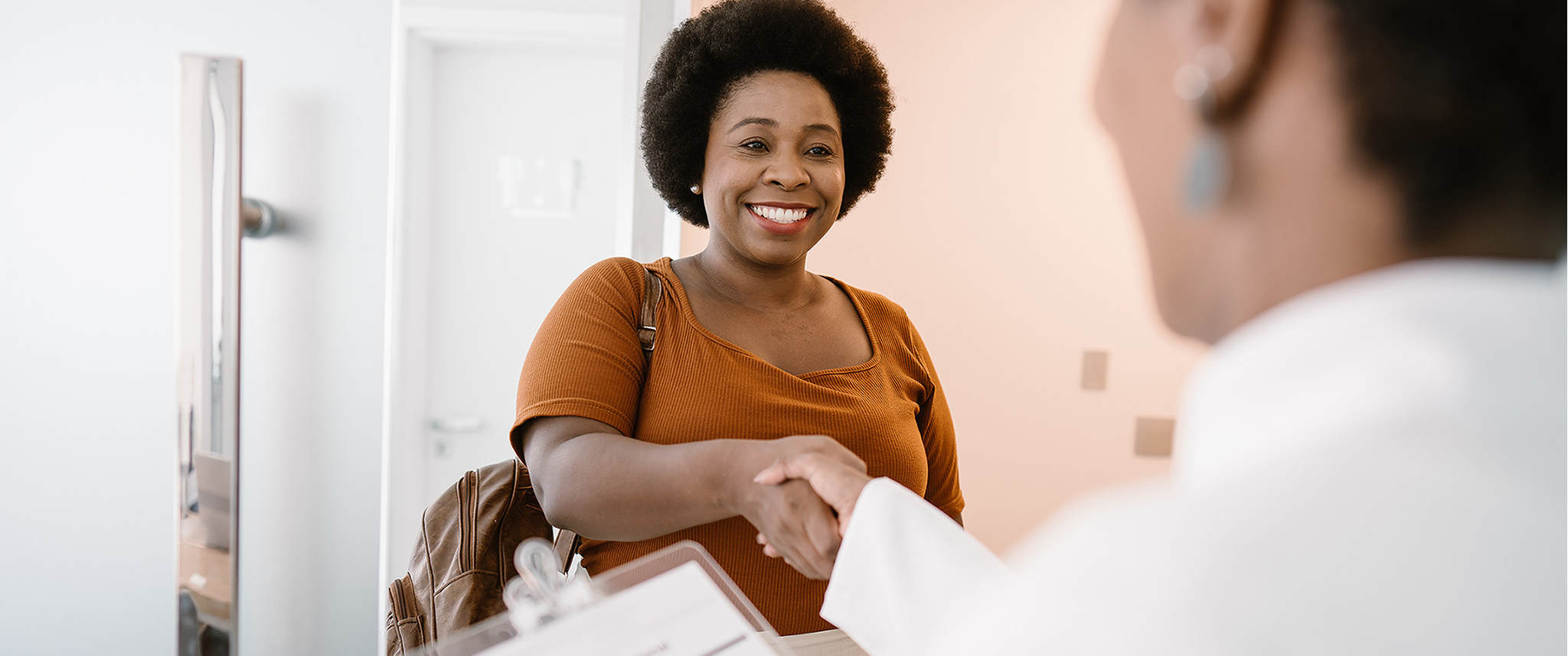 A patient is greeted as she enters a clinician's office for care.