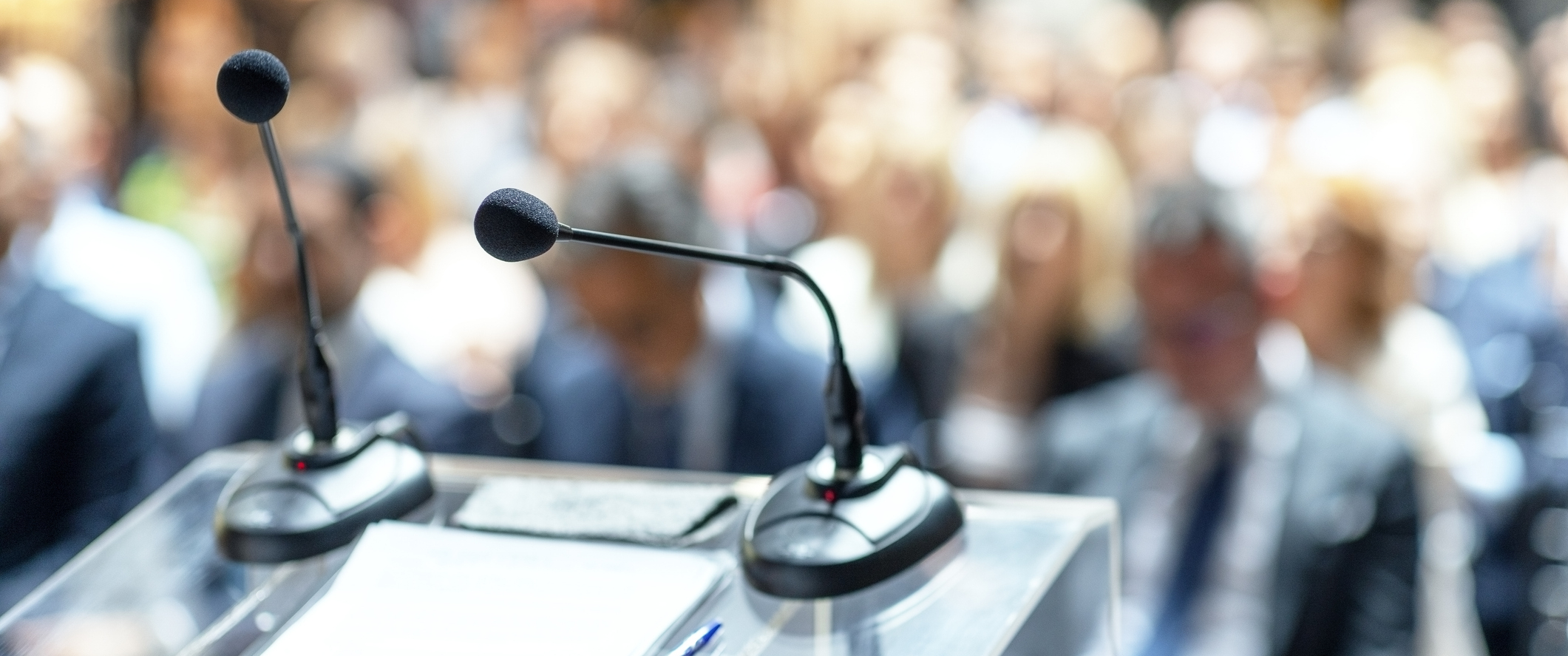 Microphones on a podium in front of an audience