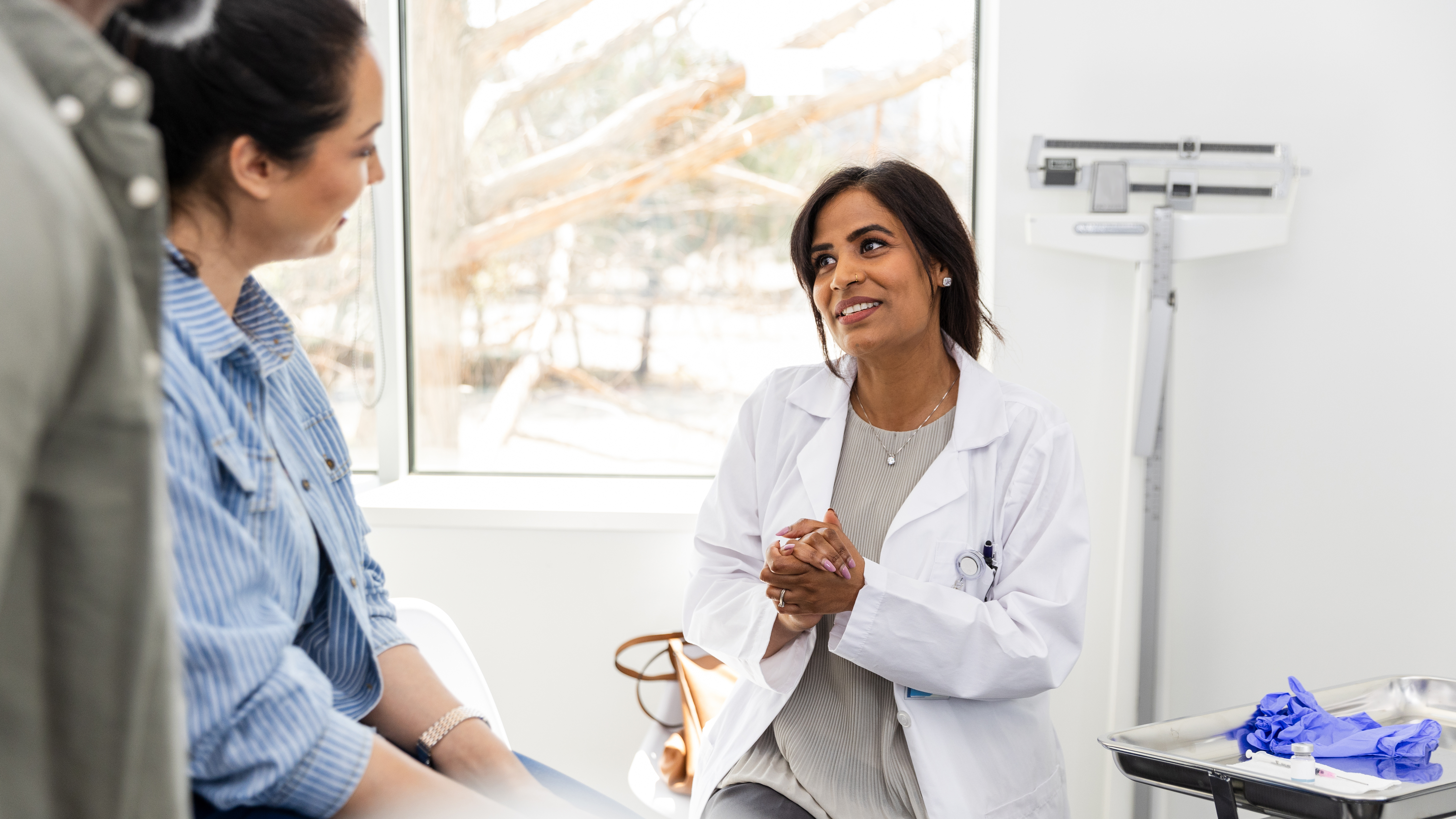 Female doctor talks with her female patient and her husband.