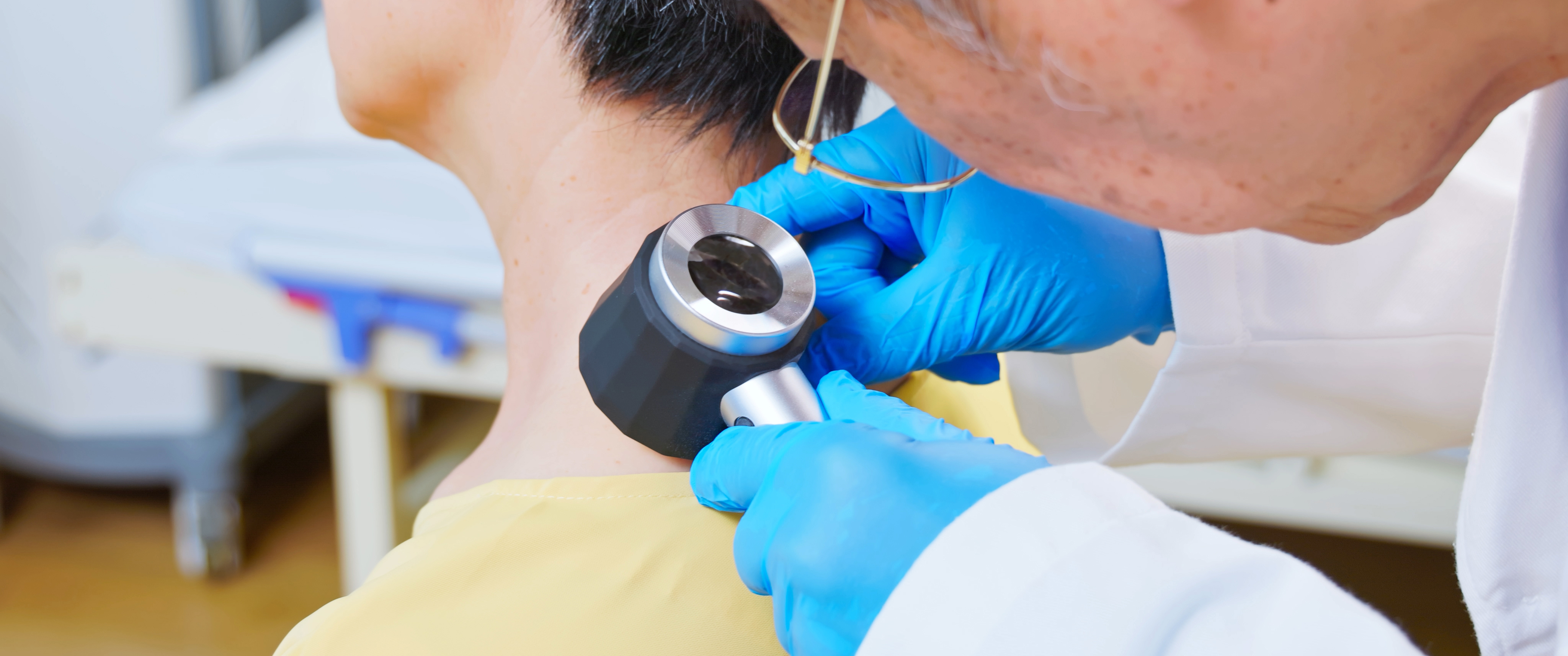 A dermatologist examines a woman’s shoulder with a magnifying glass in a clinic