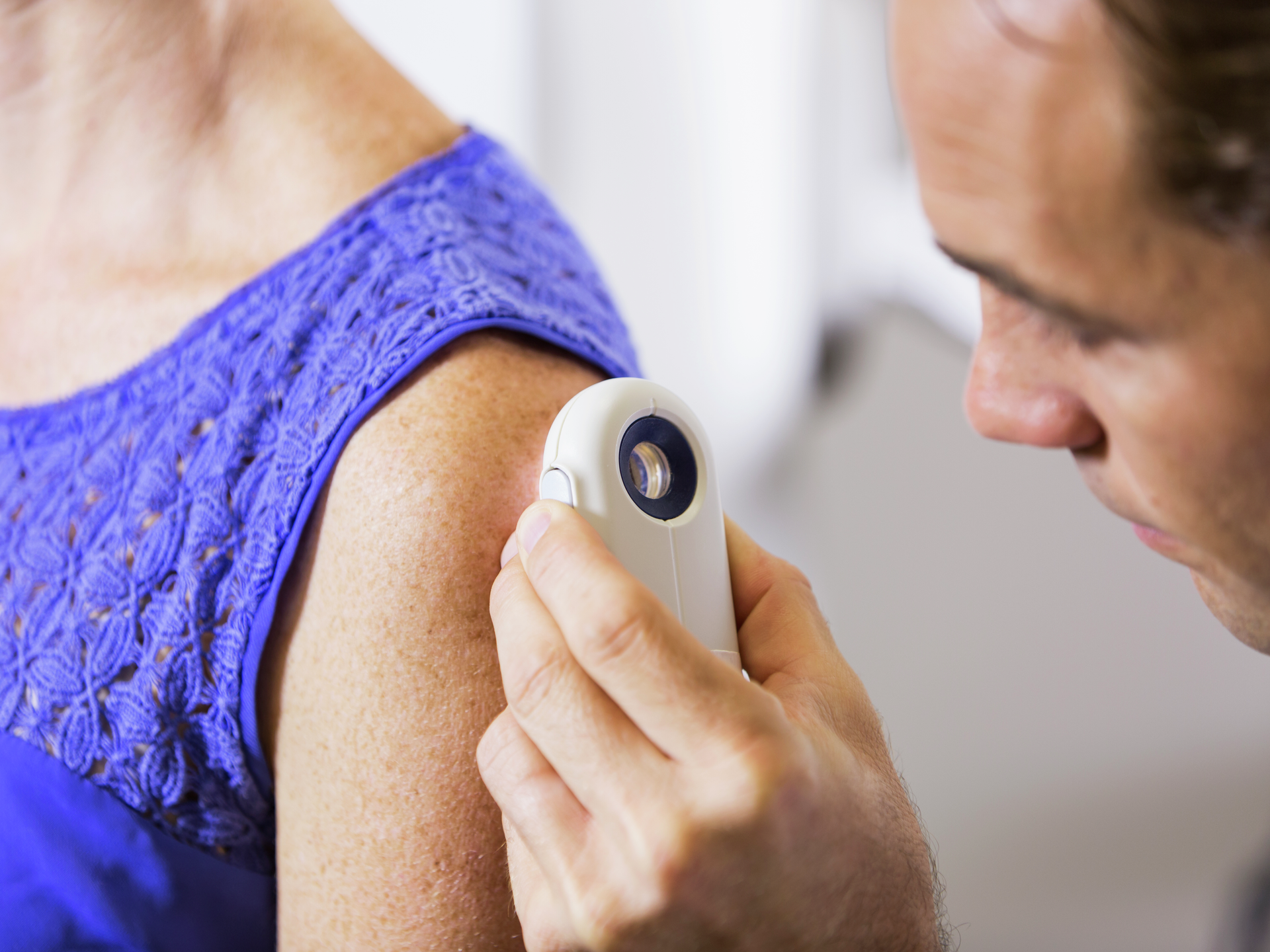 Dermatologist examines a patient's skin using a dermascope