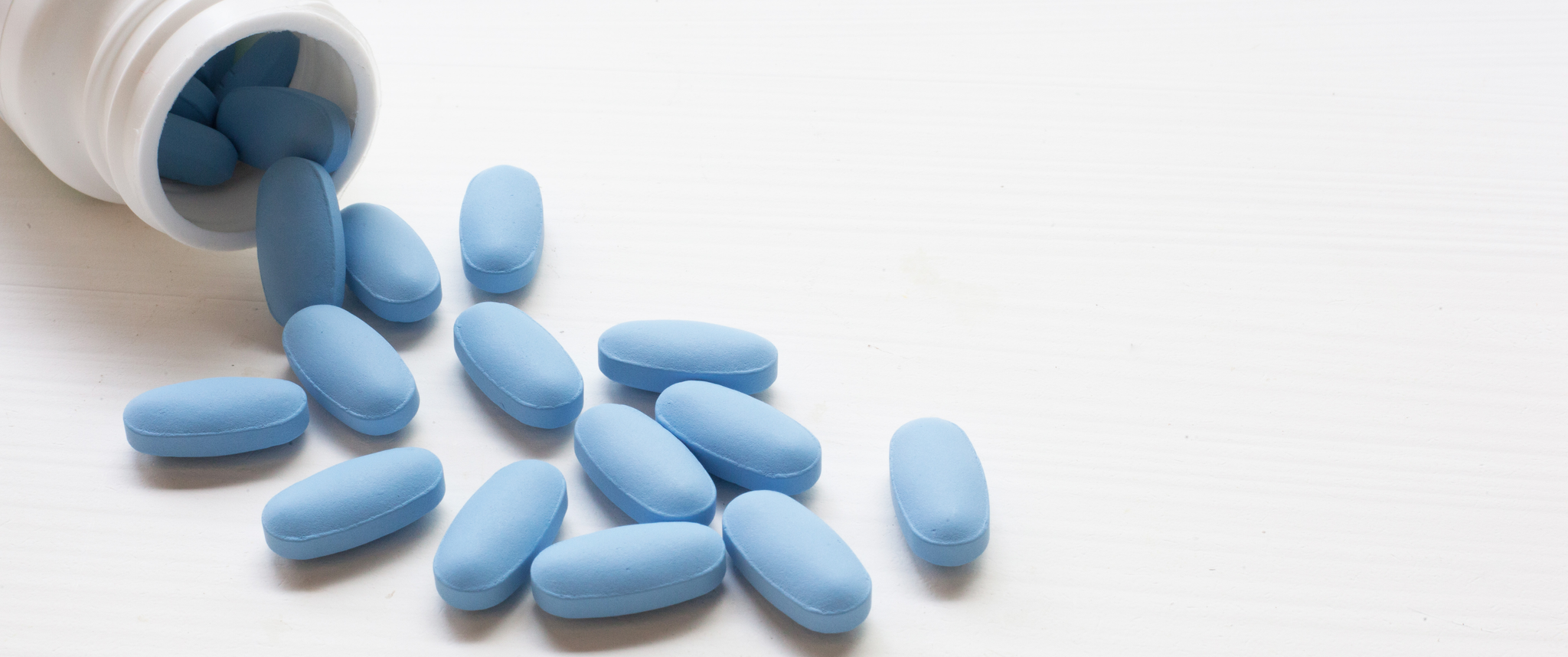 Blue pills pouring out of a bottle