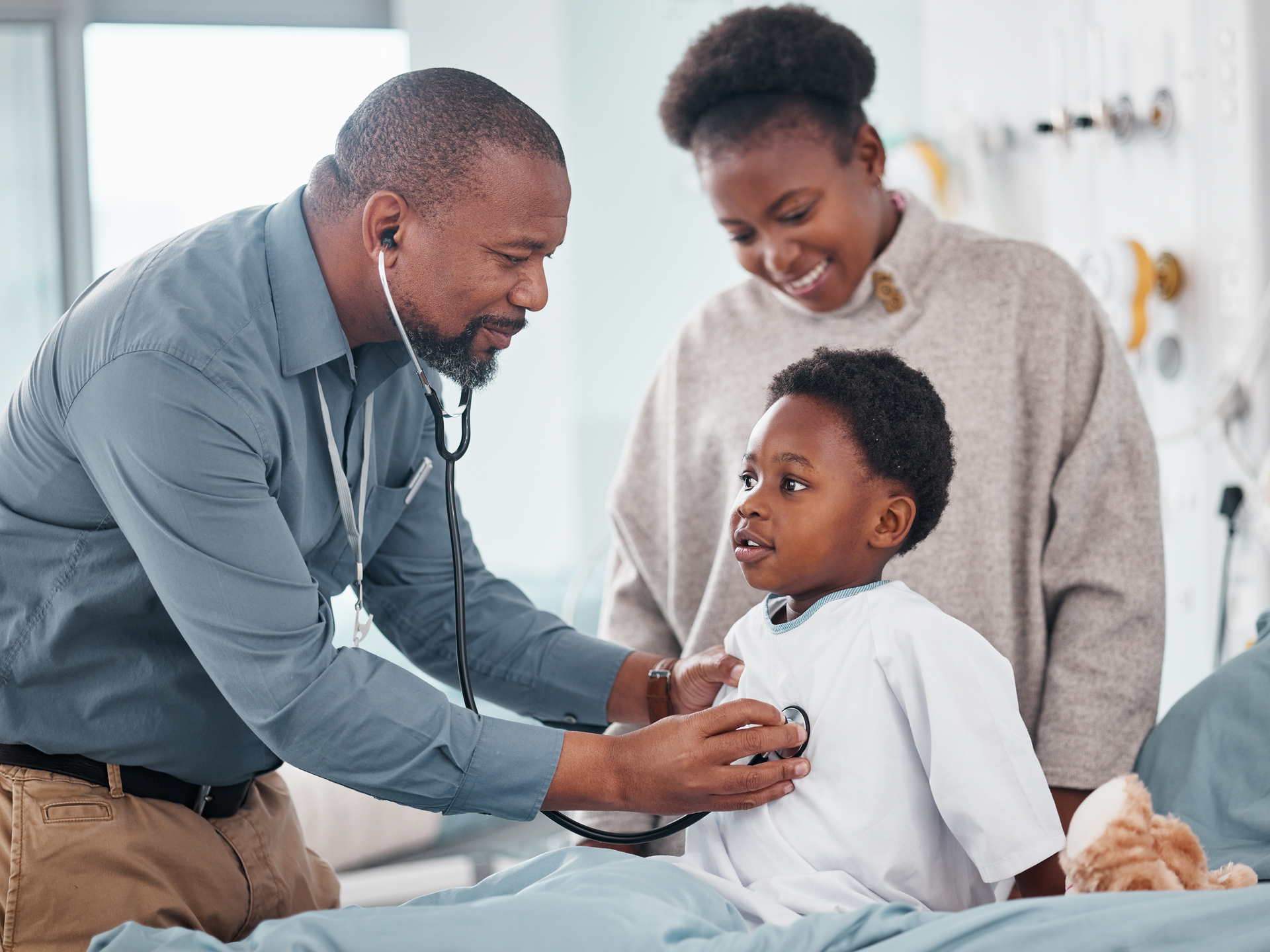 Doctor uses stethoscope on toddler while mother looks on