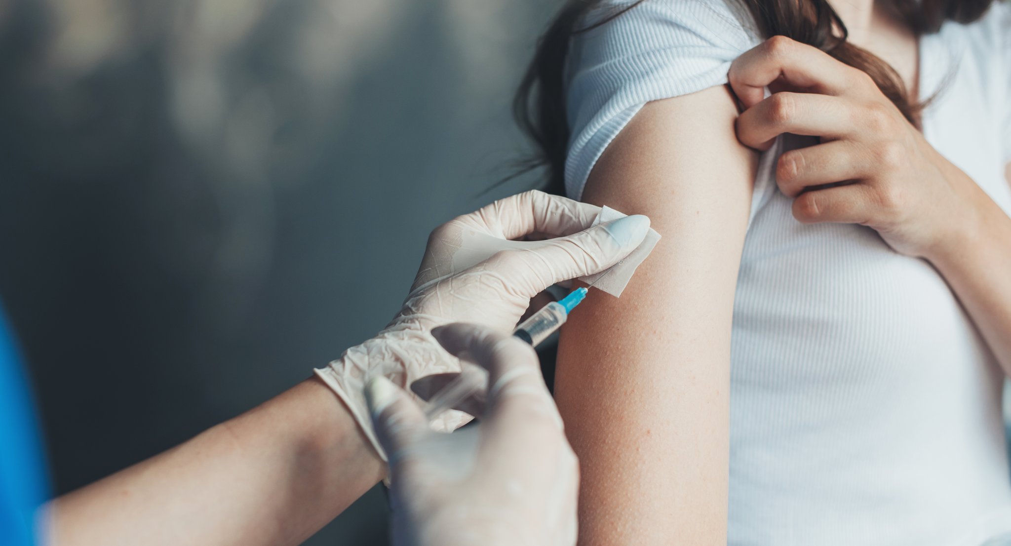 Close up of a woman receiving a vaccine in her arm from a nurse