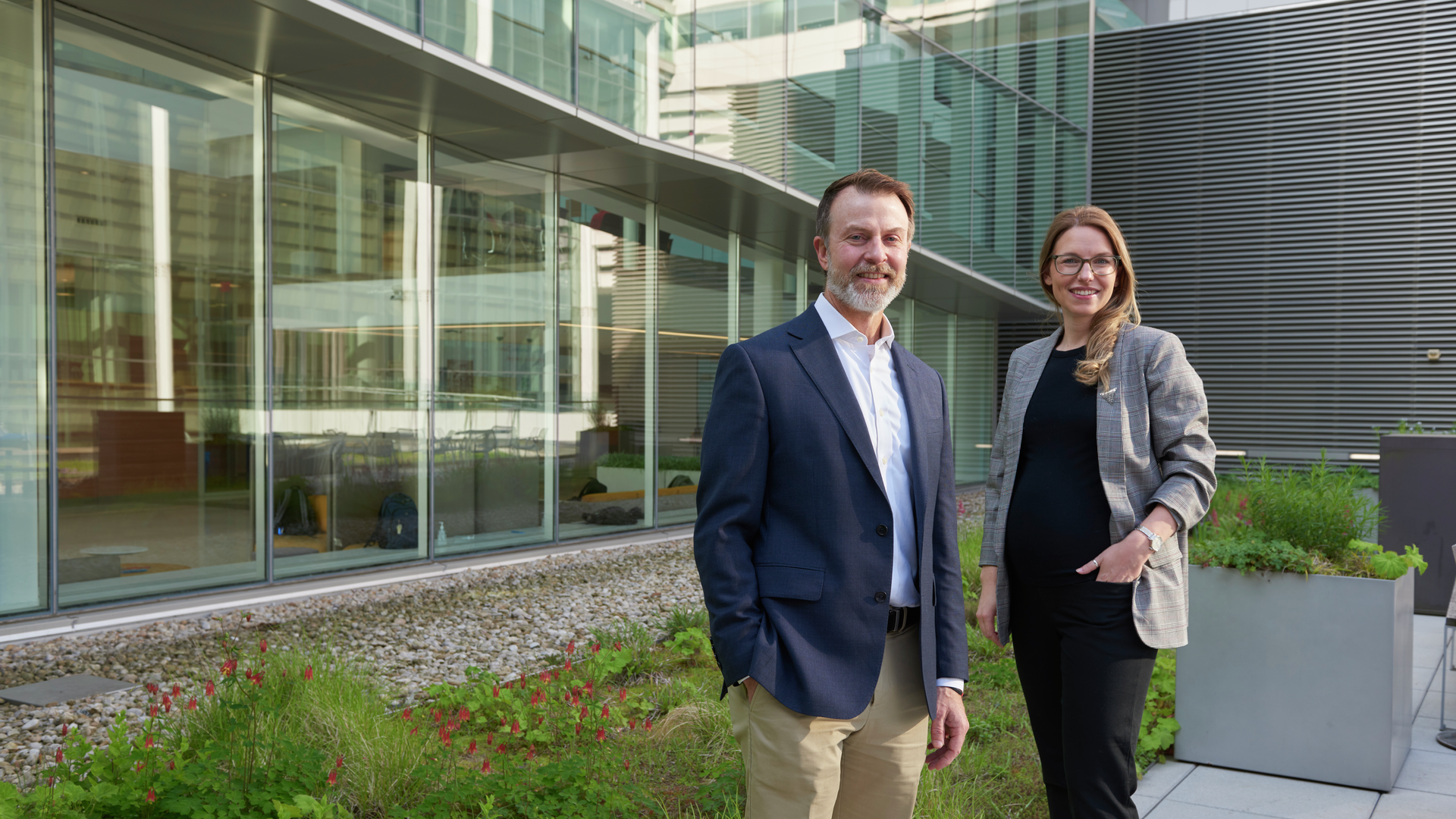 E. John Wherry and Allie Greenplate standing on an outdoor roof deck in a portrait