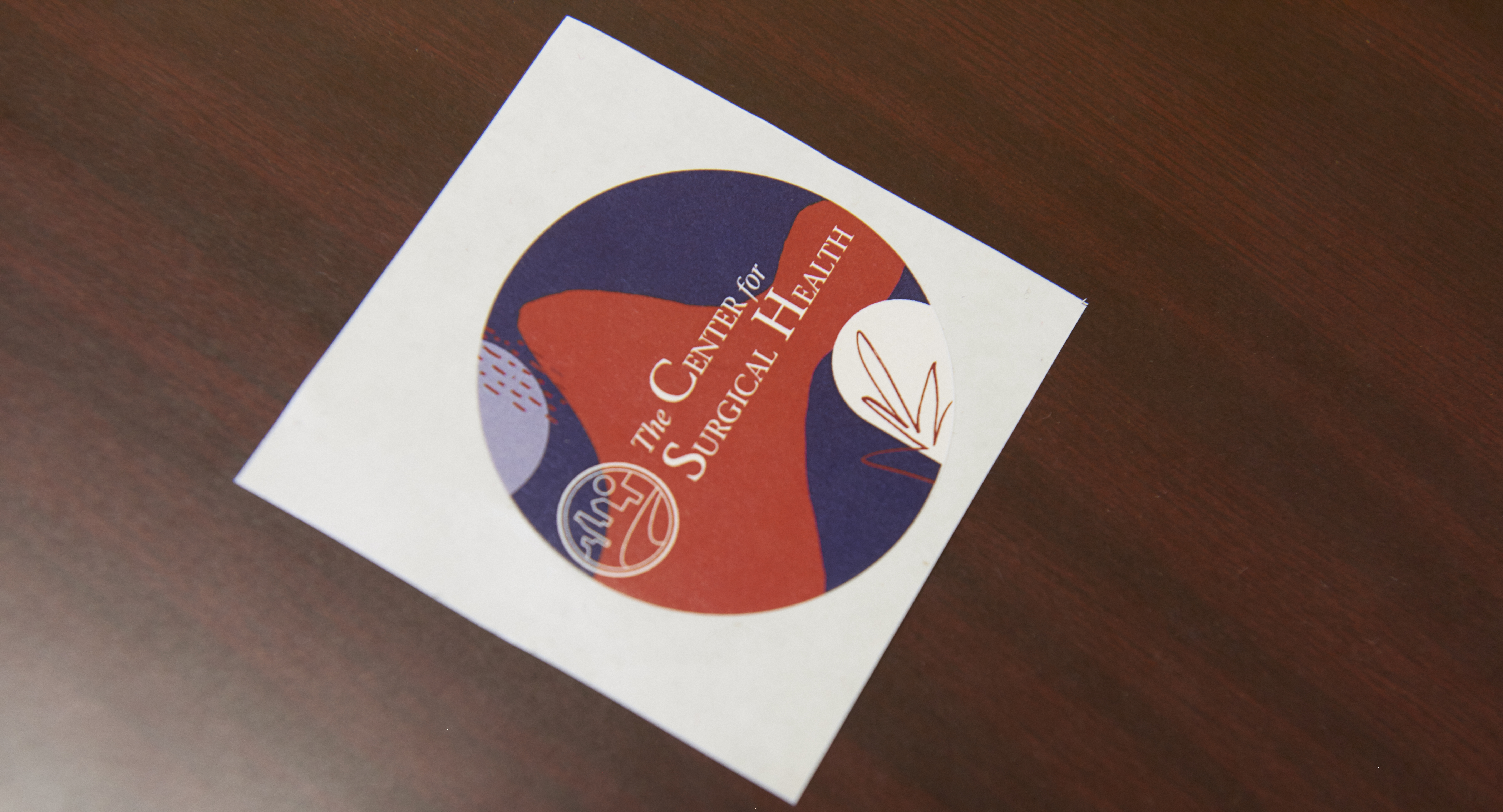 A circular sticker on a wooden table displays "The Center for Surgical Health"