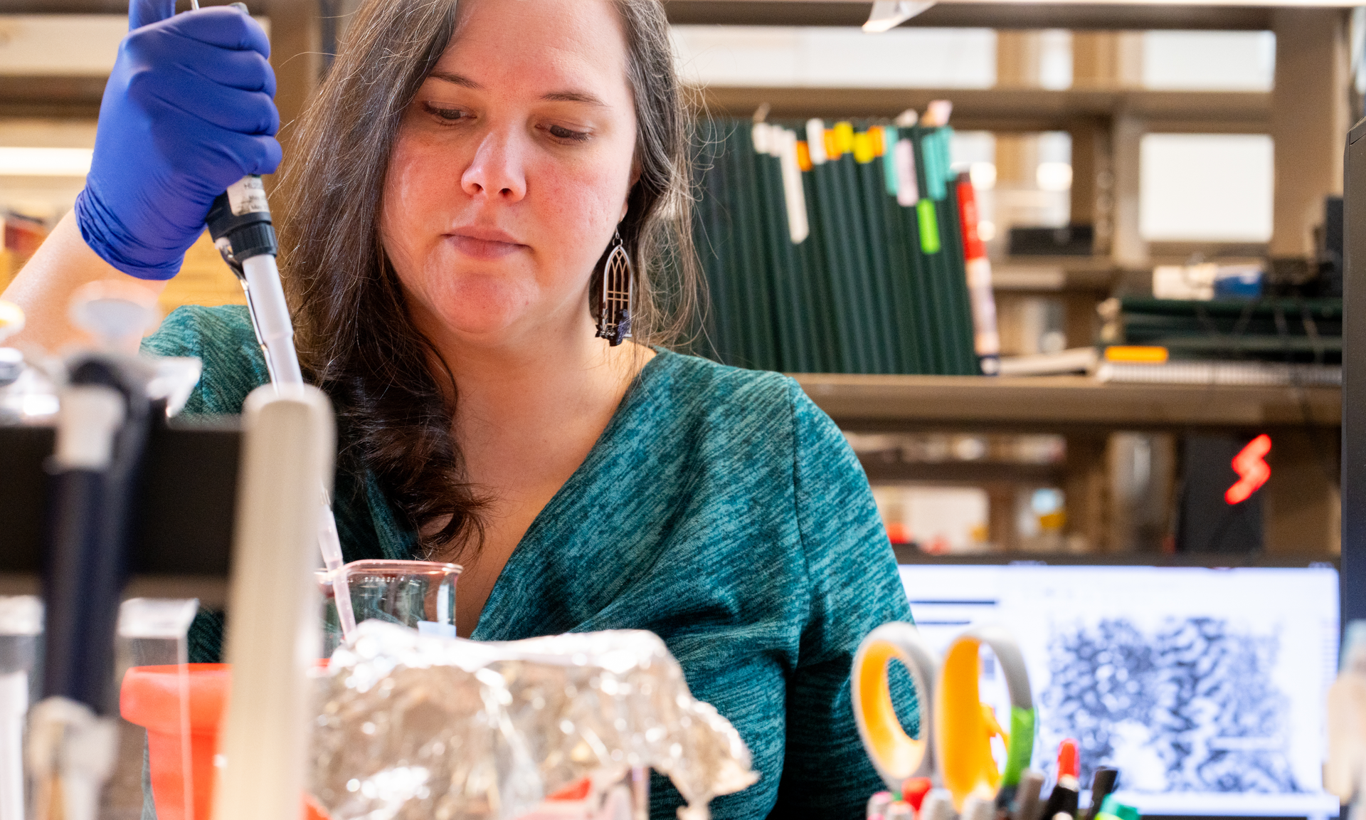 Ruth Anne Pumroy works at a lab bench holding a pipette