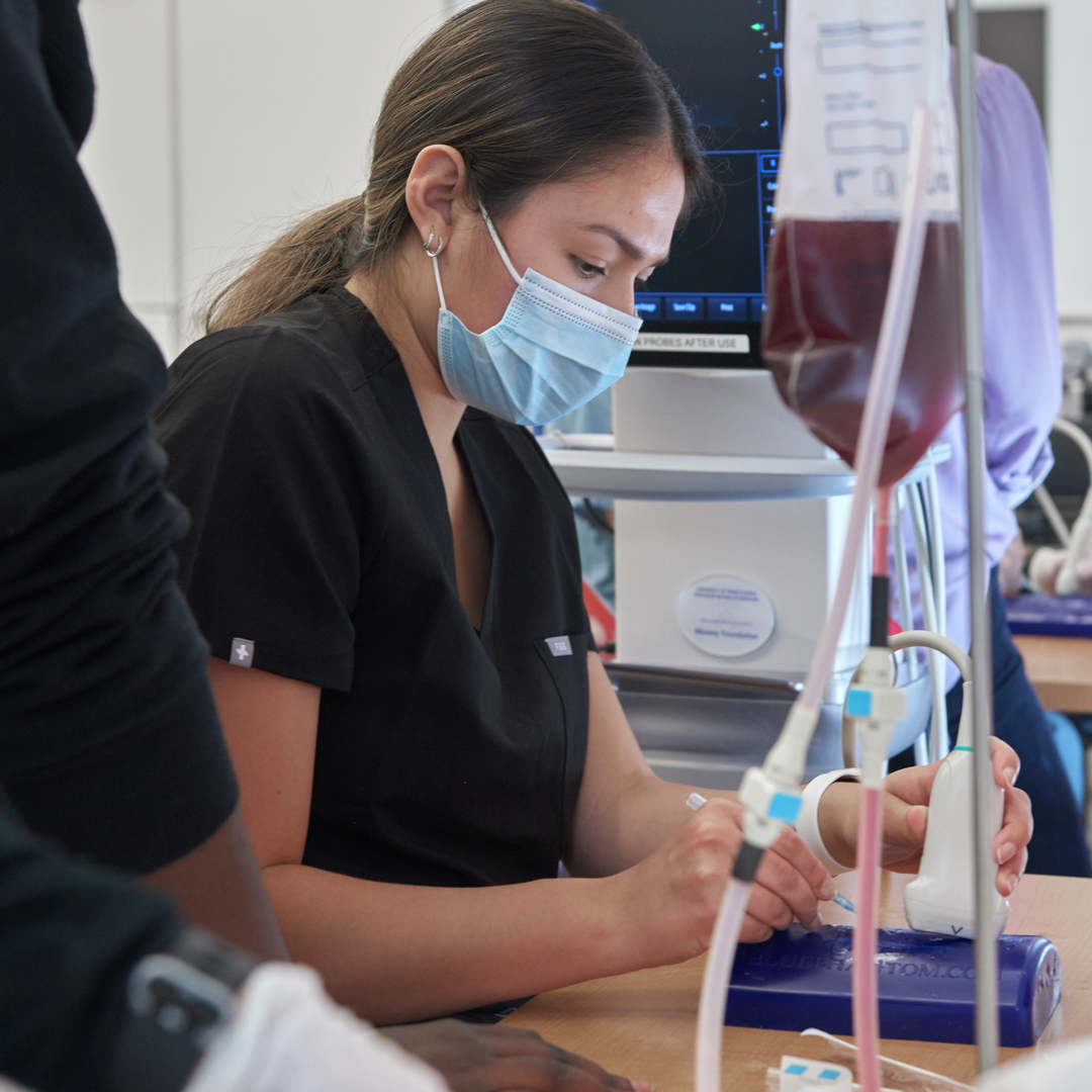 A medical student practices needle insertion guided by ultrasound in a simulator tool