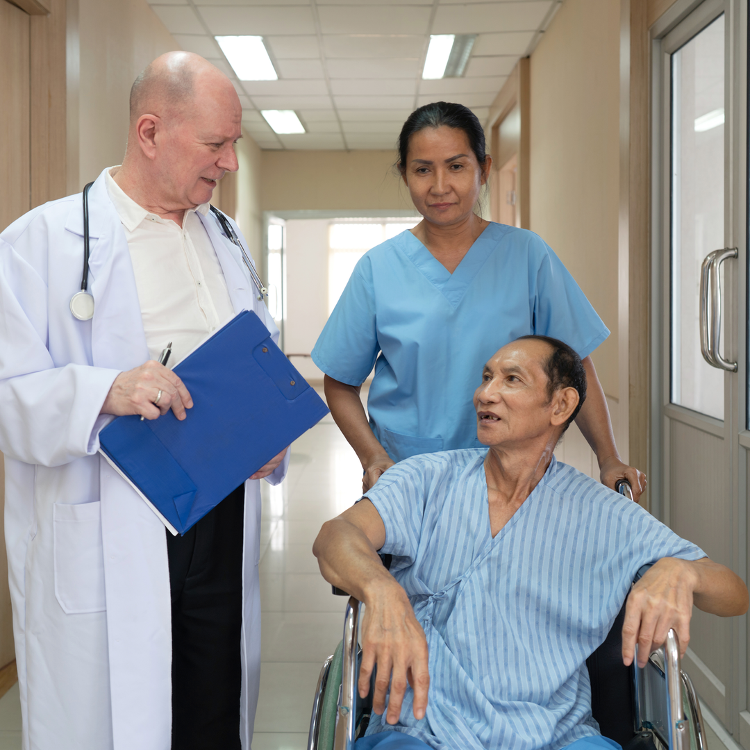 Medical staff engage with a patient in a wheelchair in a modern hospital corridor.