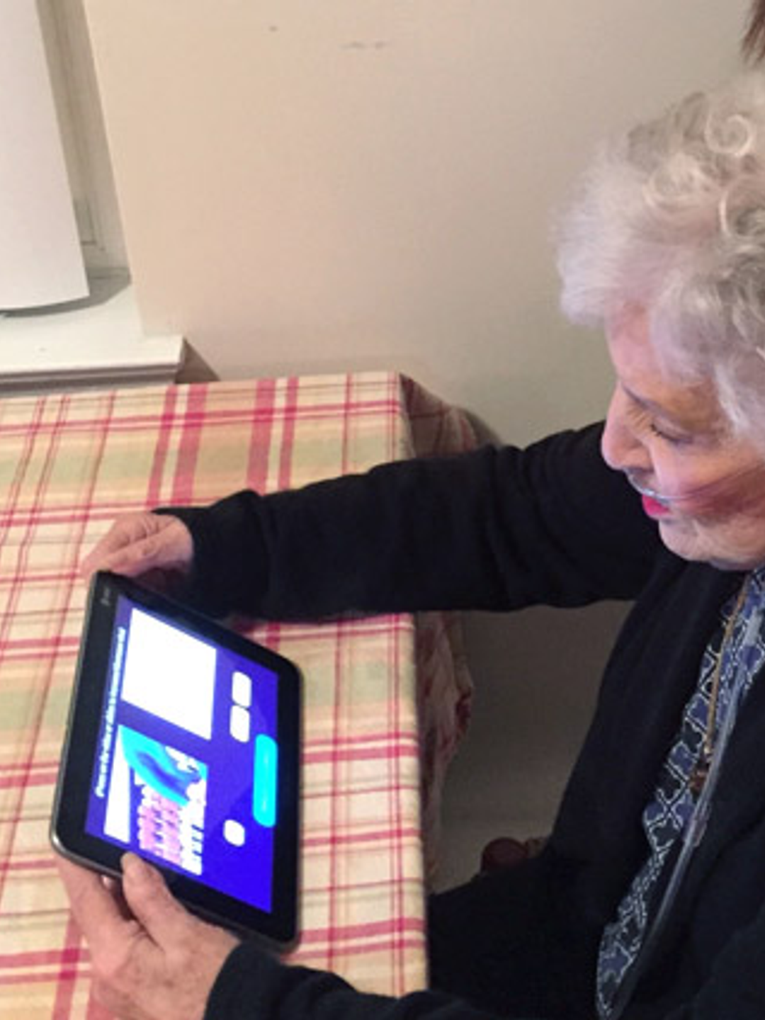 An elderly woman holds a tablet during a telehealth appointment