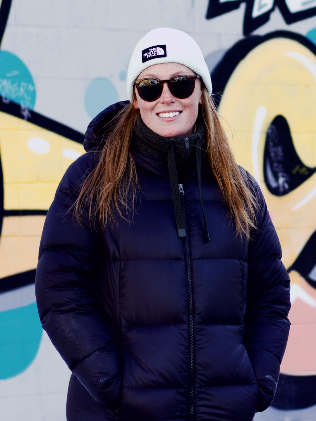 Emily Seeburger standing in front of a mural on a wall