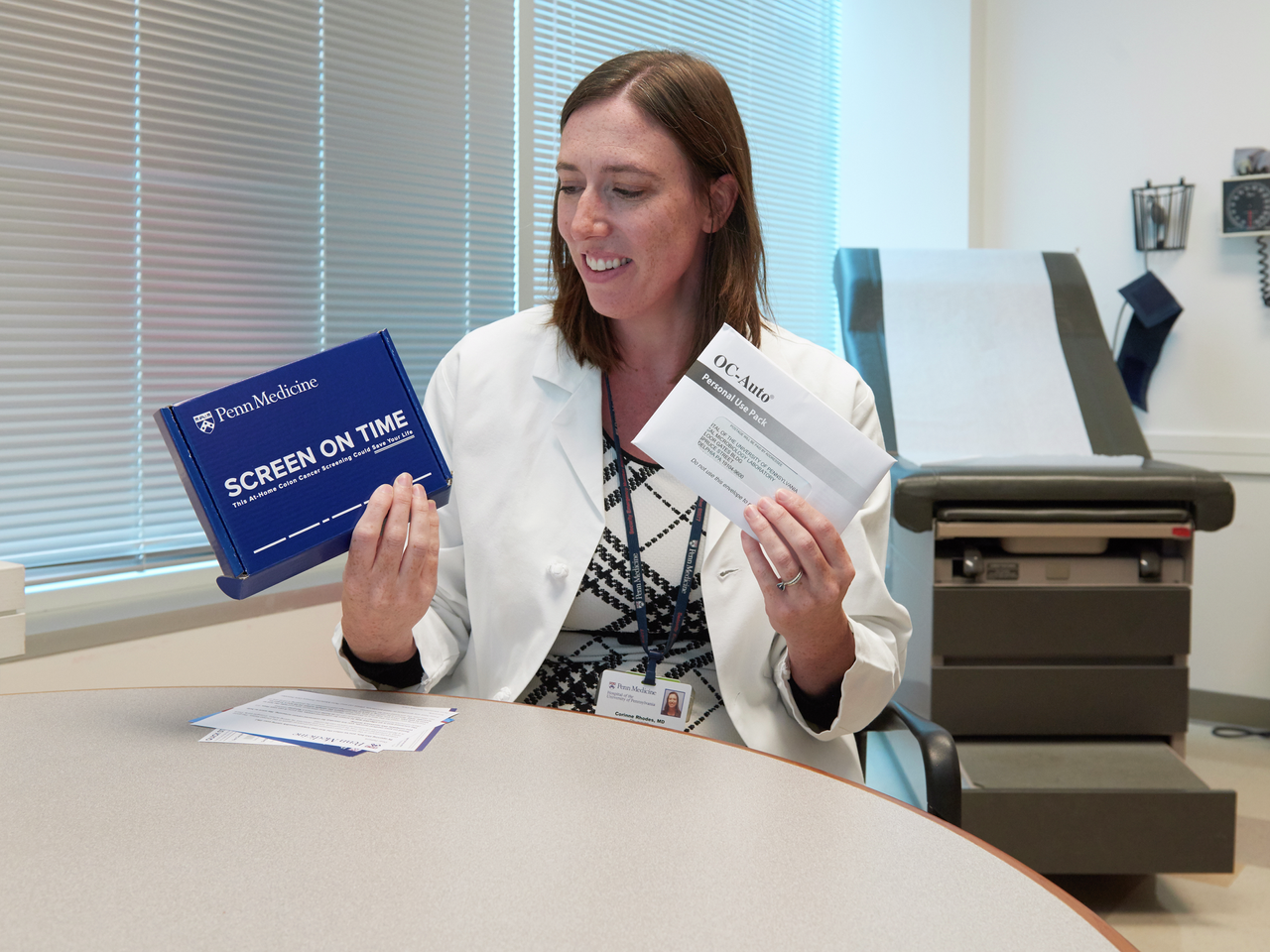 Corinne Rhodes, MD, holds up both a Penn-branded and manufacturer-branded FIT testing kit