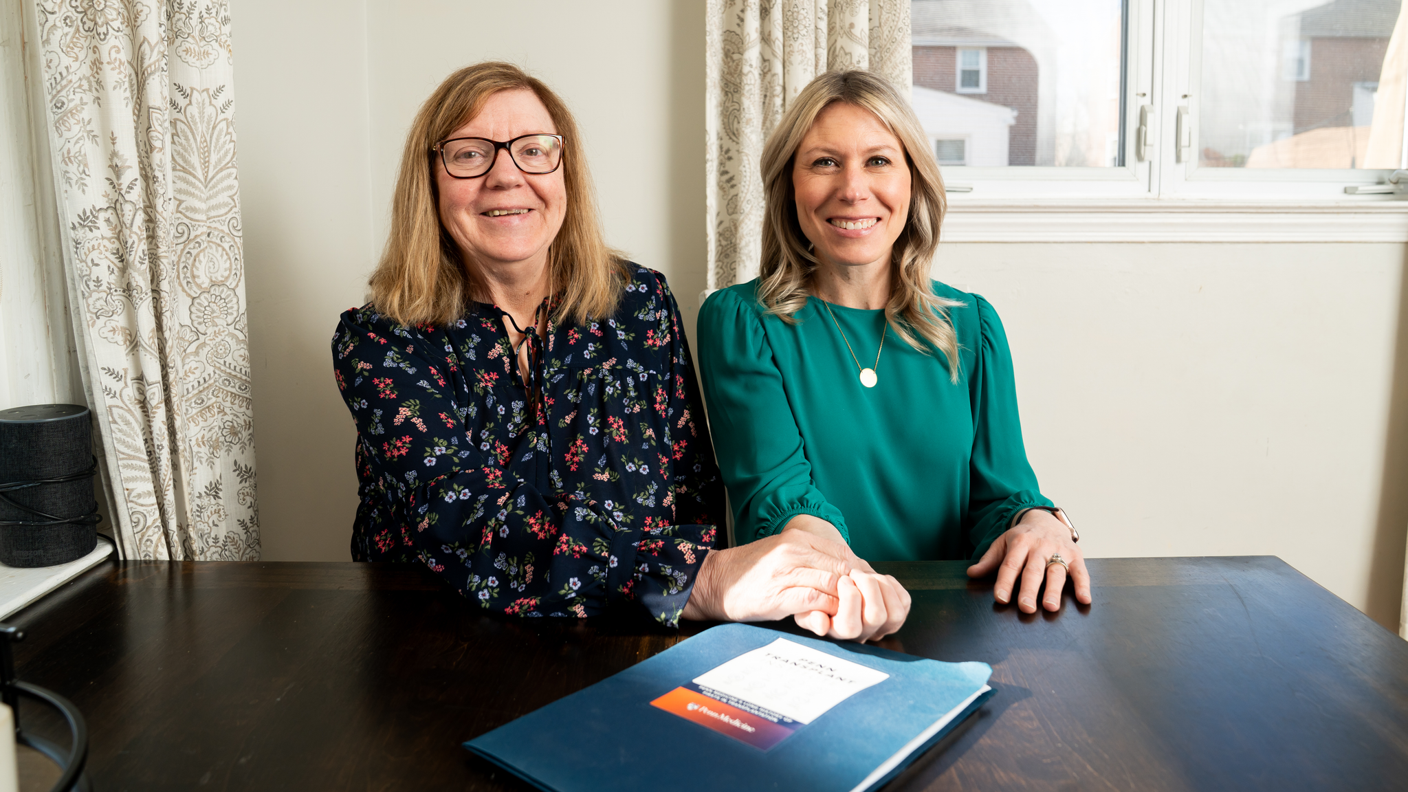 Jen Brady, right, sitting with her mom, Terri, at a table with a Penn Transplant Institute folder on it