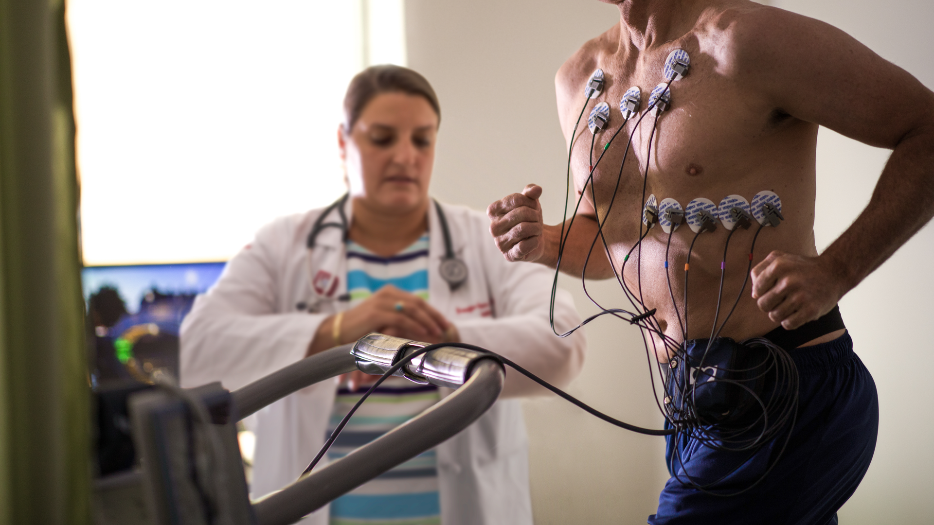 Heart and vascular nurse performs cardiology exam on patient running on treadmill