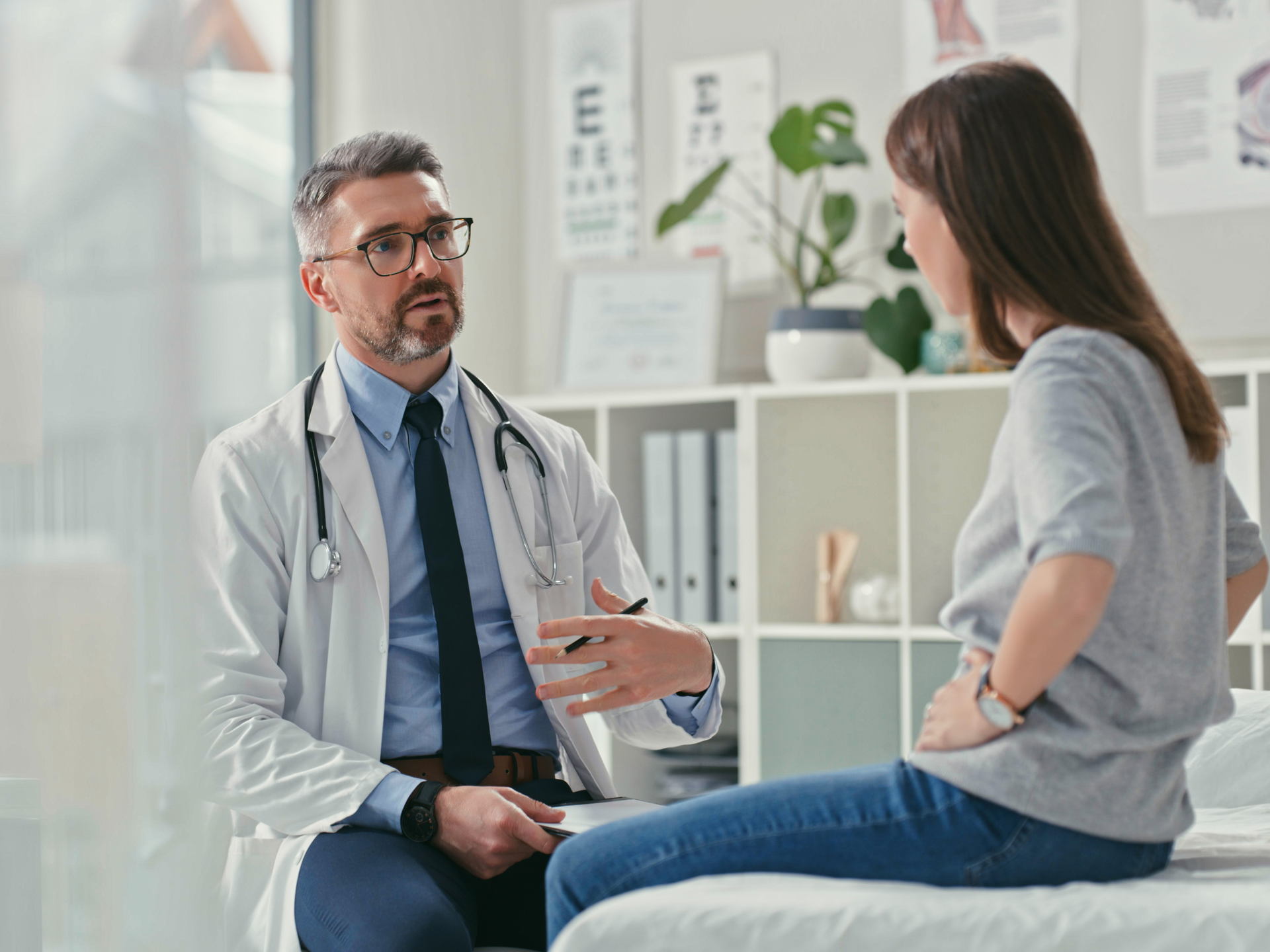 Shot of a mature doctor sitting with his patient in the clinic and asking questions during a consultation