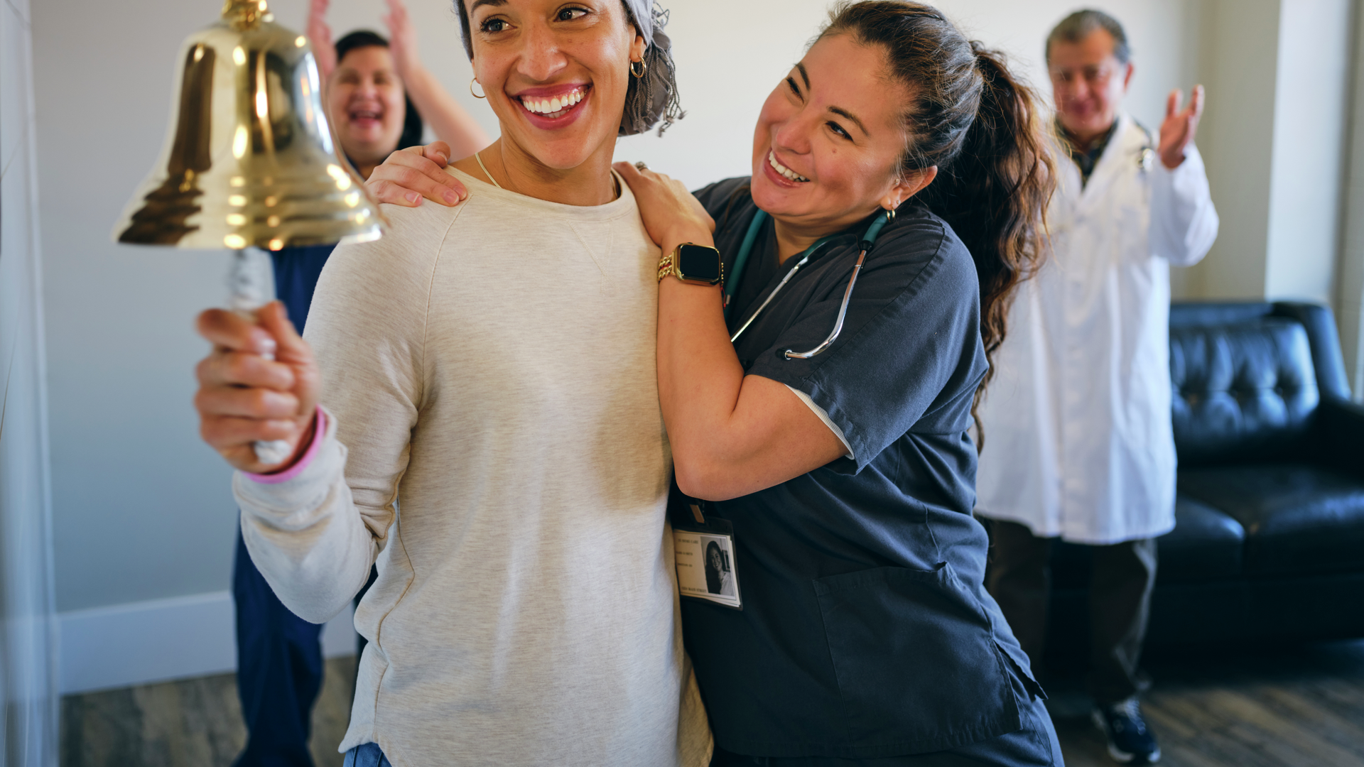 Adult woman chemotherapy patient in a treatment office, celebrating the completion of her treatment with a ceremonial bell ring