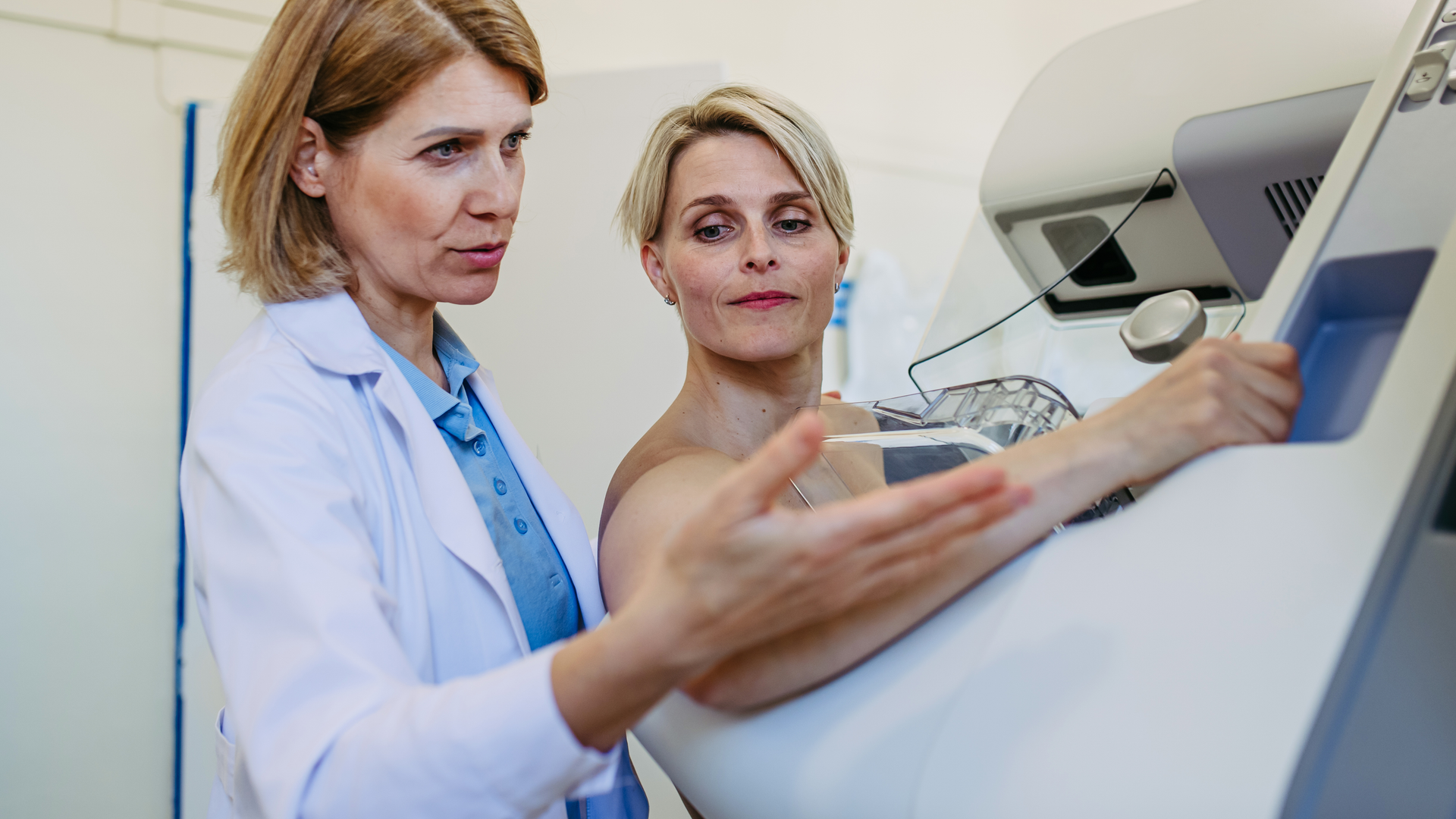 Healthcare professional adjusts the patient for accurate breast imaging. Preventive breast cancer screening.