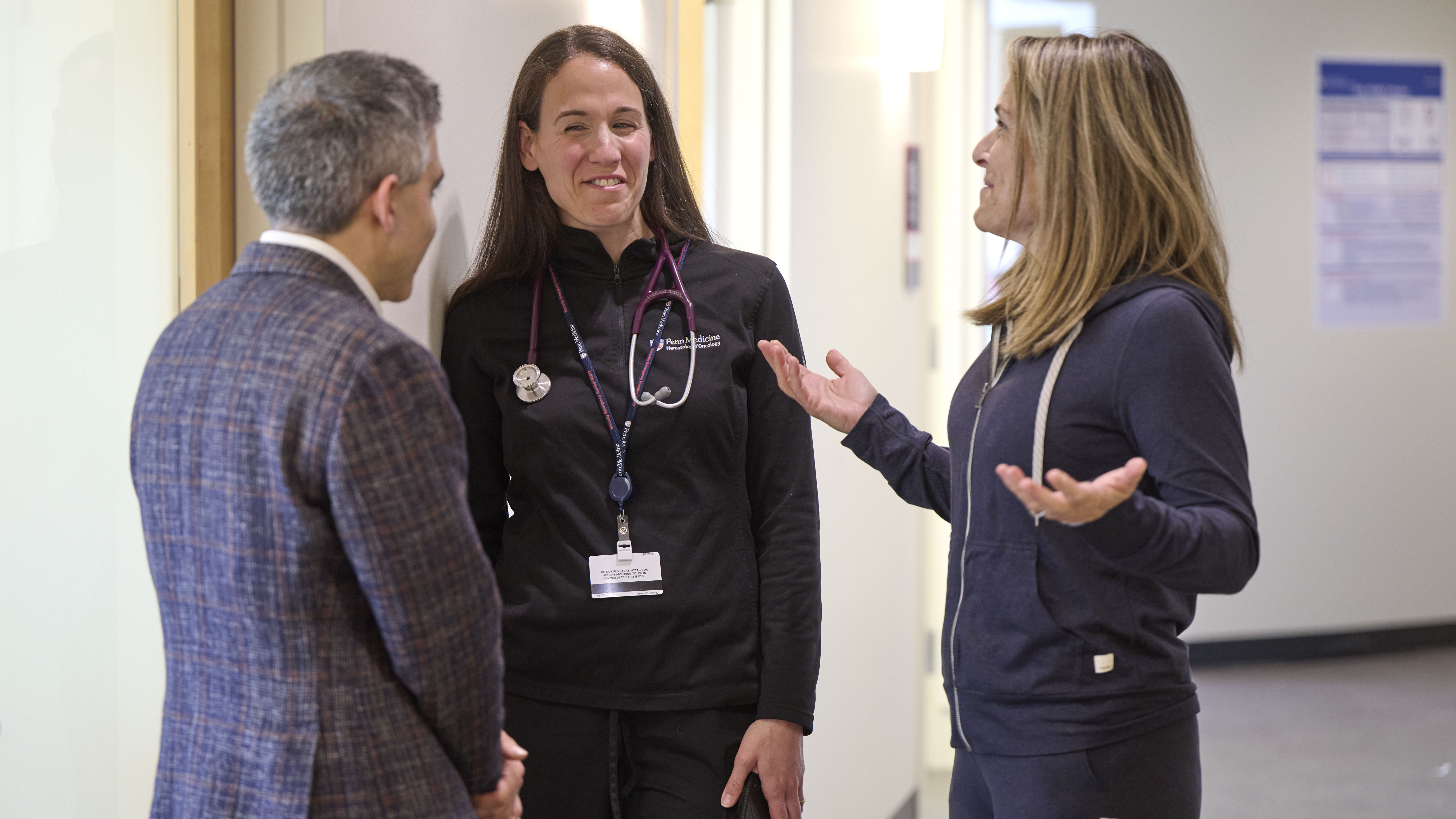 Ronac Mamtani, MD, and an oncology nurse talk with patient Amy Darragh outside of a chemotherapy infusion room