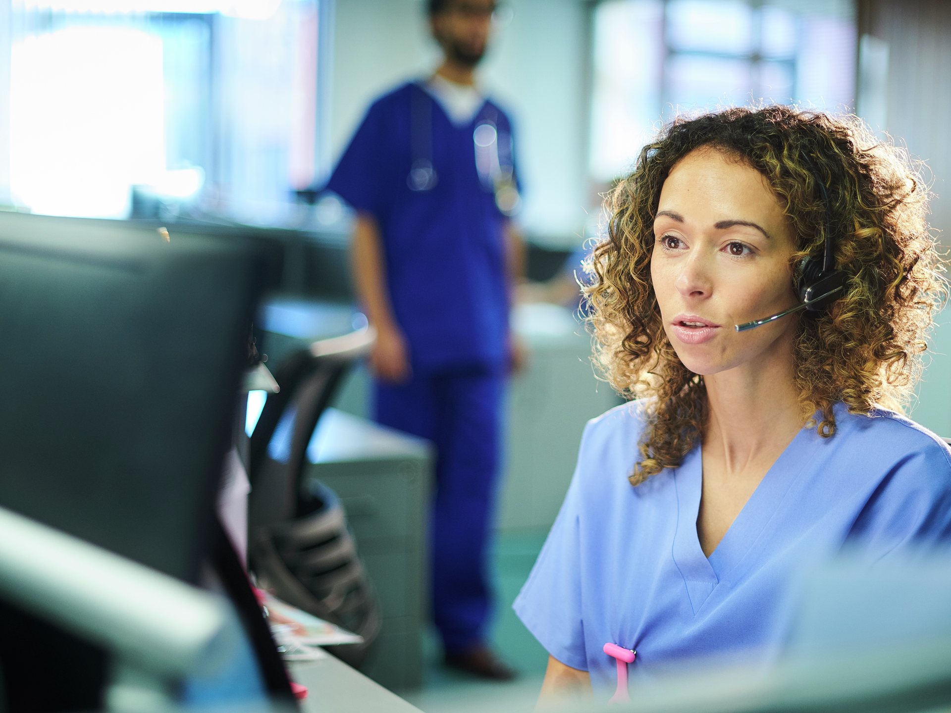 Nurse at a desk at the hospital on a phone headset 