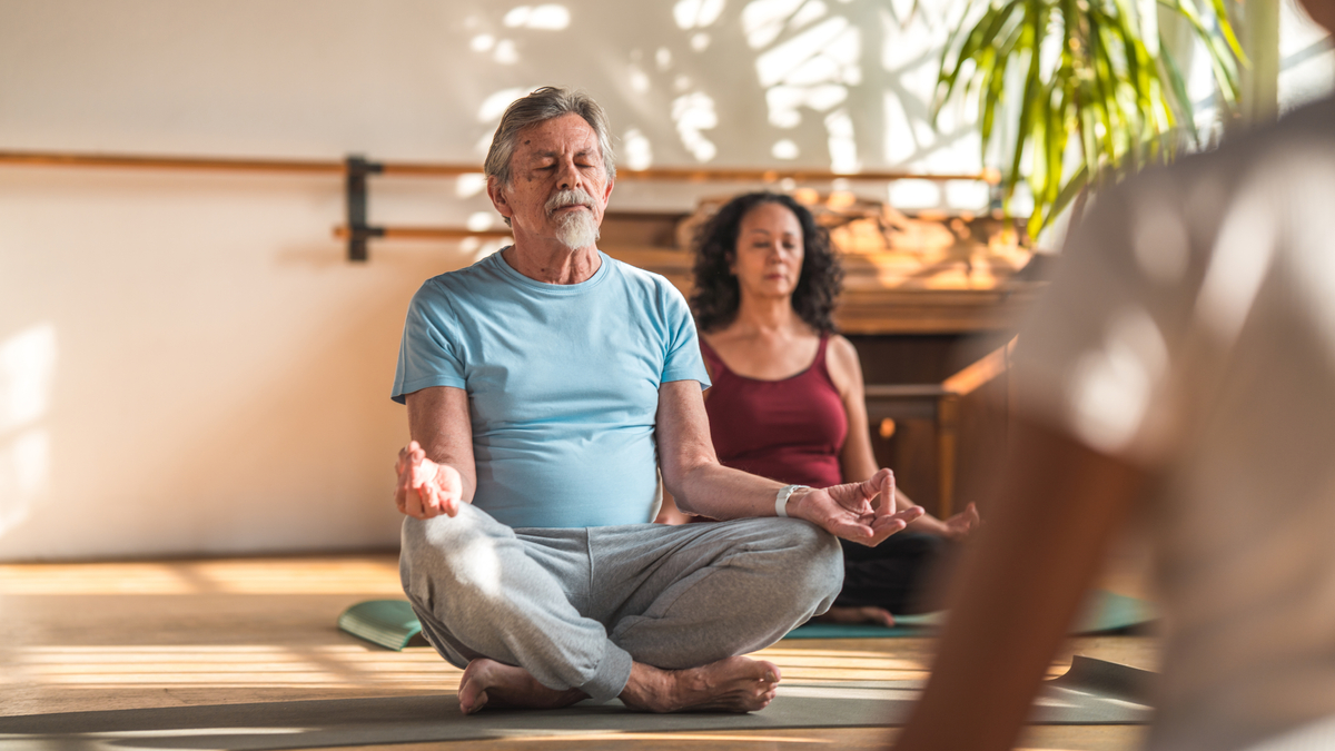 Seniors practicing meditation in yoga studio. 
