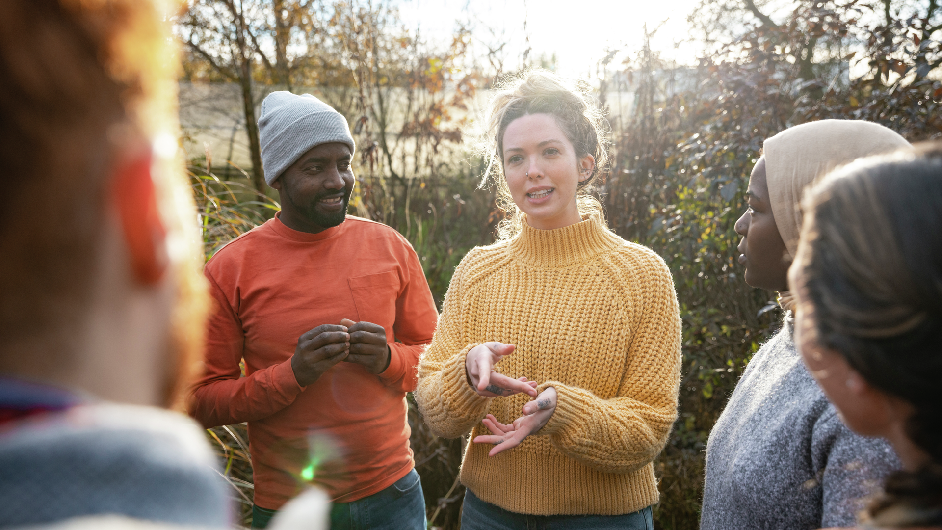 A multiracial group of volunteers wearing warm casual clothing and accessories on a sunny cold winters day.