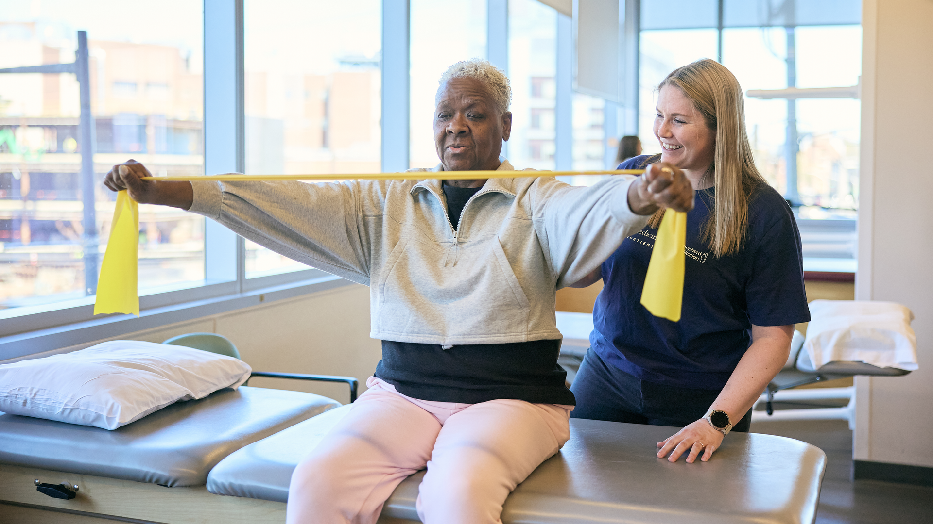 Patient uses resistance bands while physical therapist looks on at Good Shepard Penn Partners outpatient facility