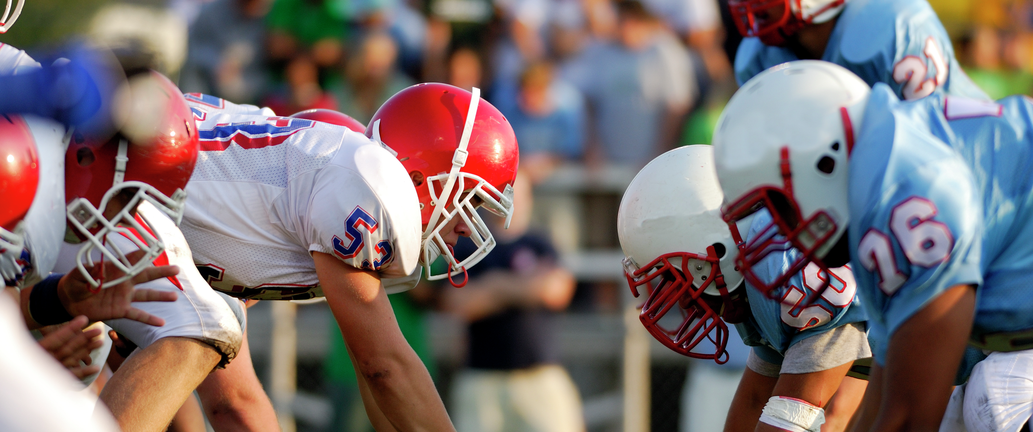 Youth football players wearing helmets in a line of scrimmage