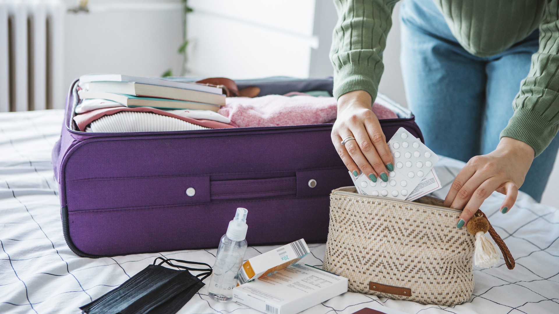 Woman preparing travel suitcase on bed at home