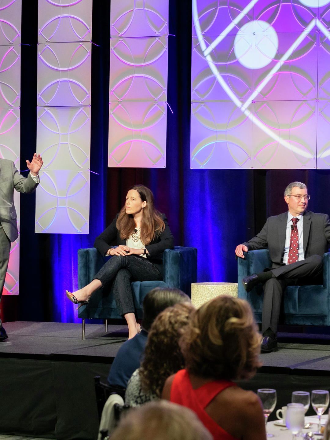 Jonathan Epstein, MD, stands at a podium on  stage  where Ryan Offer, Douglas Jacoby, and Flavia Vitale are seated