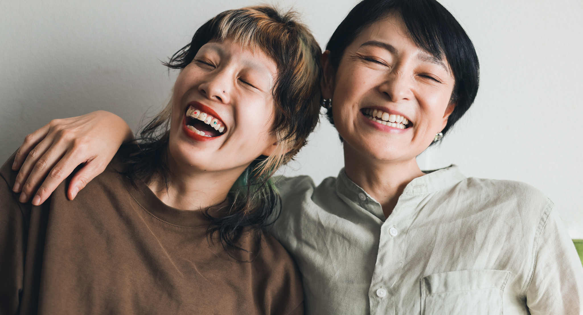Two women laughing and leaning on each other
