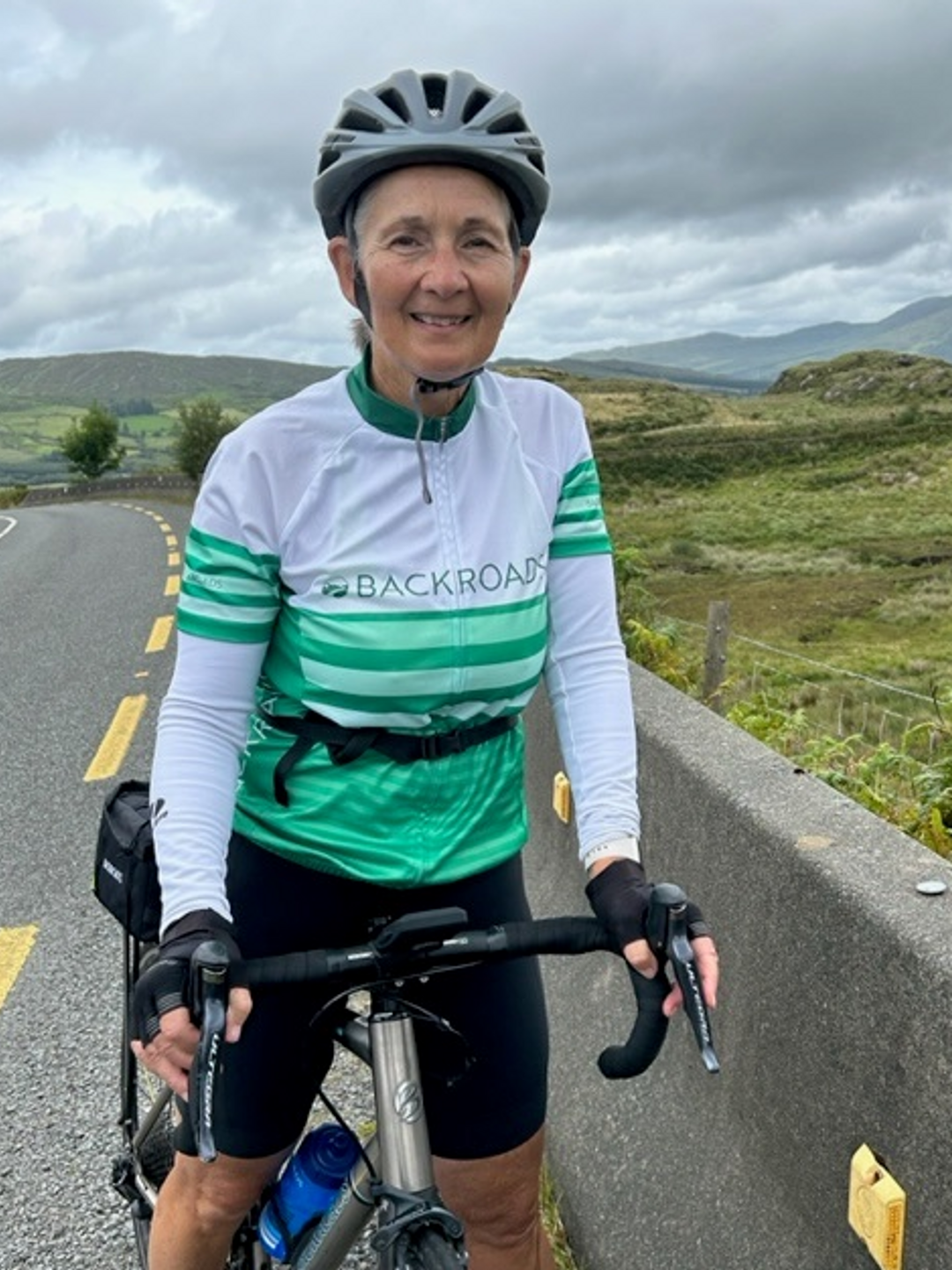 Kathleen Tierney standing at a roadside in bicycle gear with a bike
