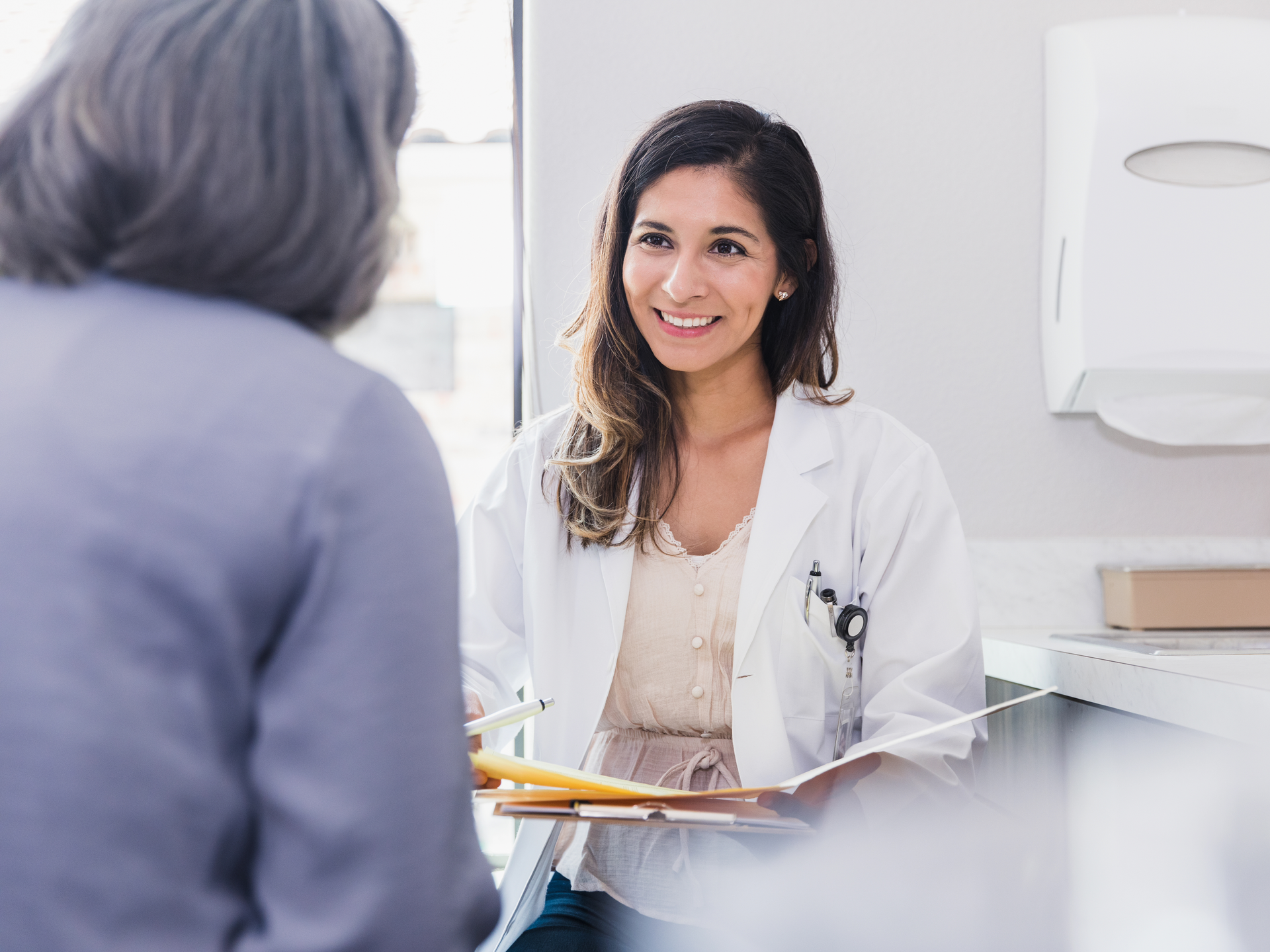 Female doctor smiles while listening to a female patient discuss her health during an annual medical exam